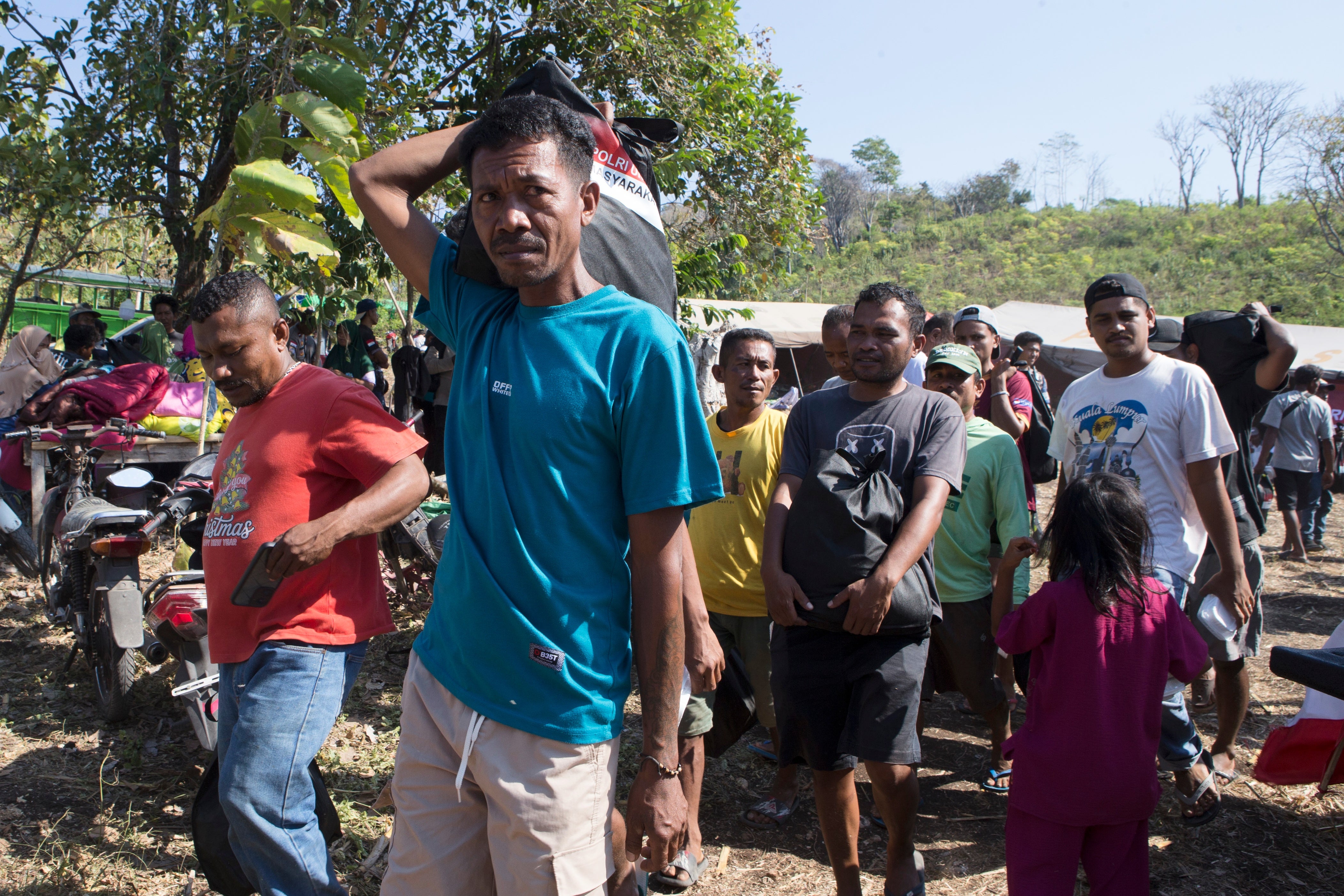 Earthquake survivors carry relief goods in North Lamba Leda, East Nusa Tenggara province, Indonesia