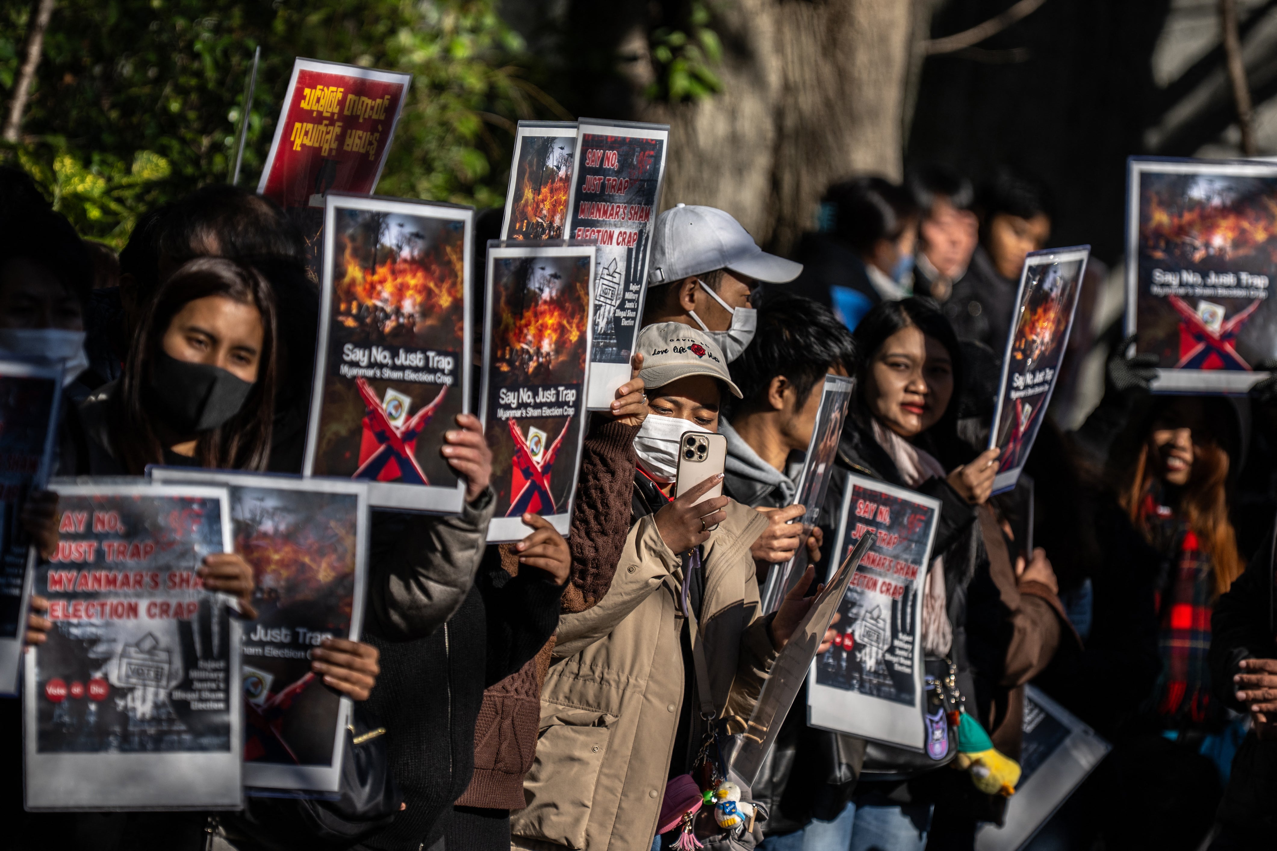 Demonstrators holds placards that read "say no, just trap - Myanmar's sham election crap" during a rally protesting against Myanmar's general election staged by the country's military government