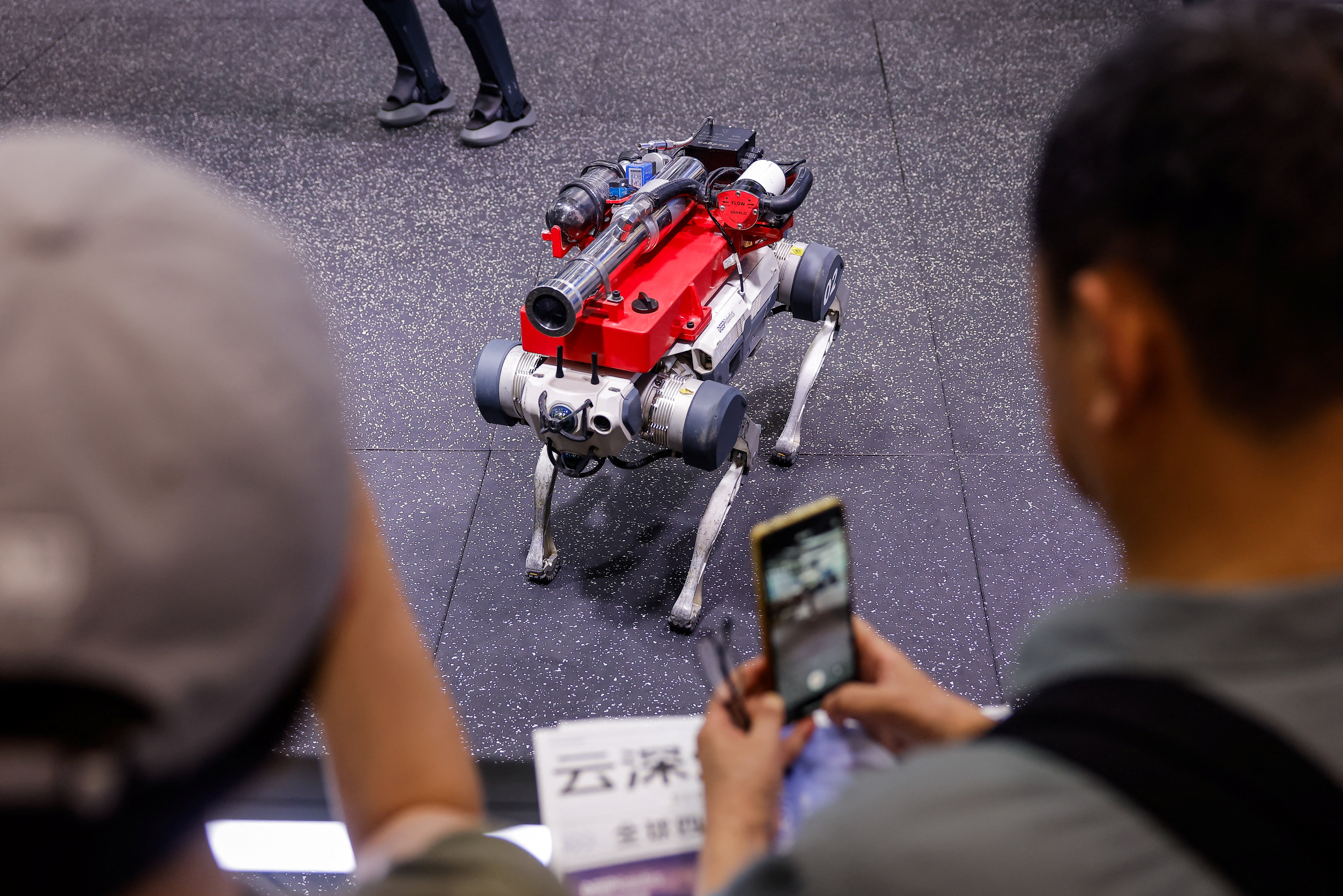 People take pictures of a Deep Robotics X30 robot dog at the company's booth at the 2026 World Robot Conference (Reuters)