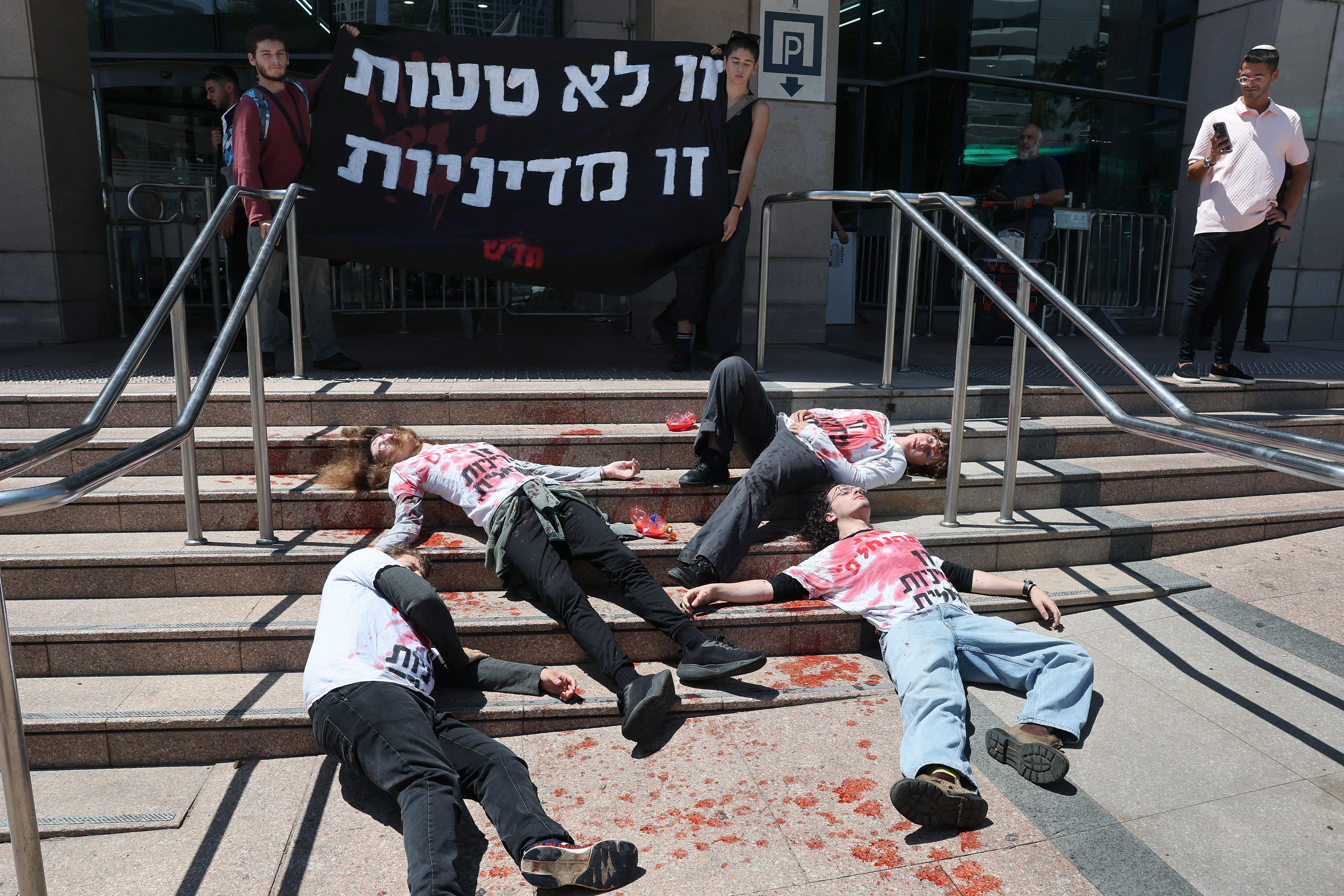 Activists in red-stained T-shirts take part in a die-in protest in the Israeli coastal city of Tel Aviv on August 19, 2026, against recent violent attacks by Israeli settlers in the Israeli-occupied West Bank (AFP/Getty)