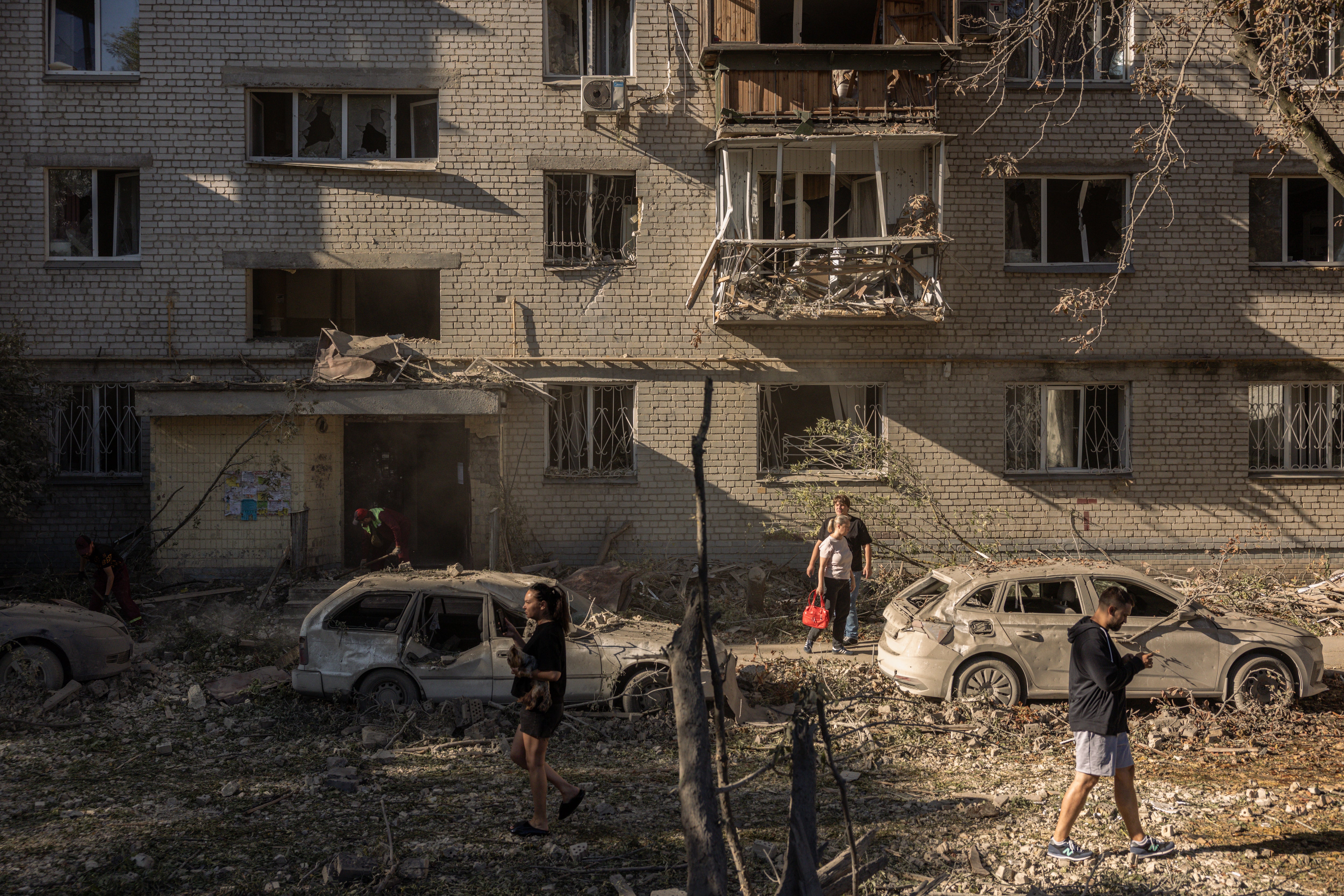 Residents walk through debris in a courtyard following a Russian missile strike on August 20, 2026 in Kyiv, Ukraine. Apartment blocks and warehouses were hit across the city overnight following a large barrage of missiles, with a children's hospital and school also damaged