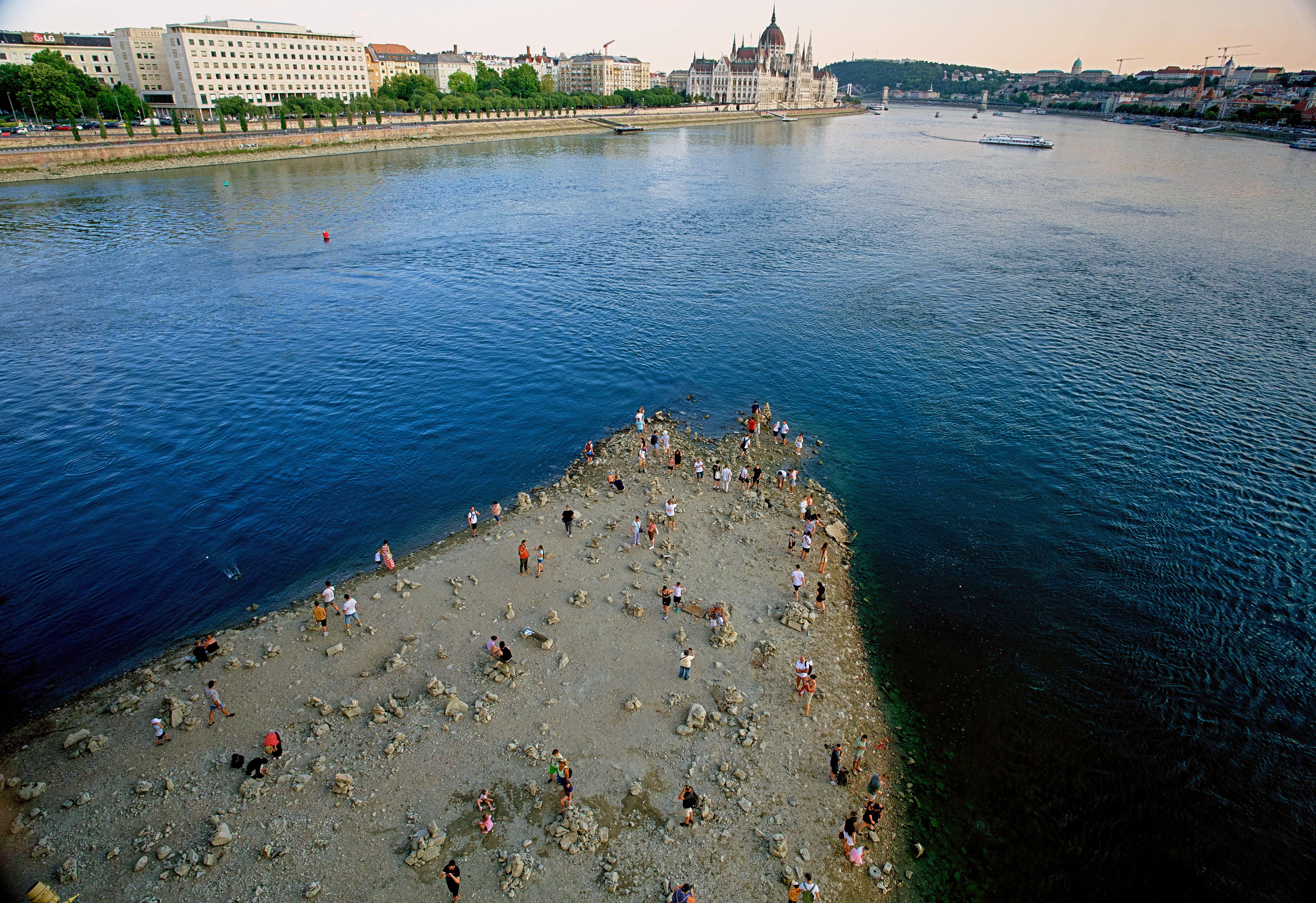 People walk on a sandbar underneath the Danube's Margareth Bridge in downtown Budapest, Hungary, on Aug. 5, 2026, as the river, which runs through 10 European countries, has receded never-before-seen low water levels. (AP Photo/Bela Szandelszky, File)