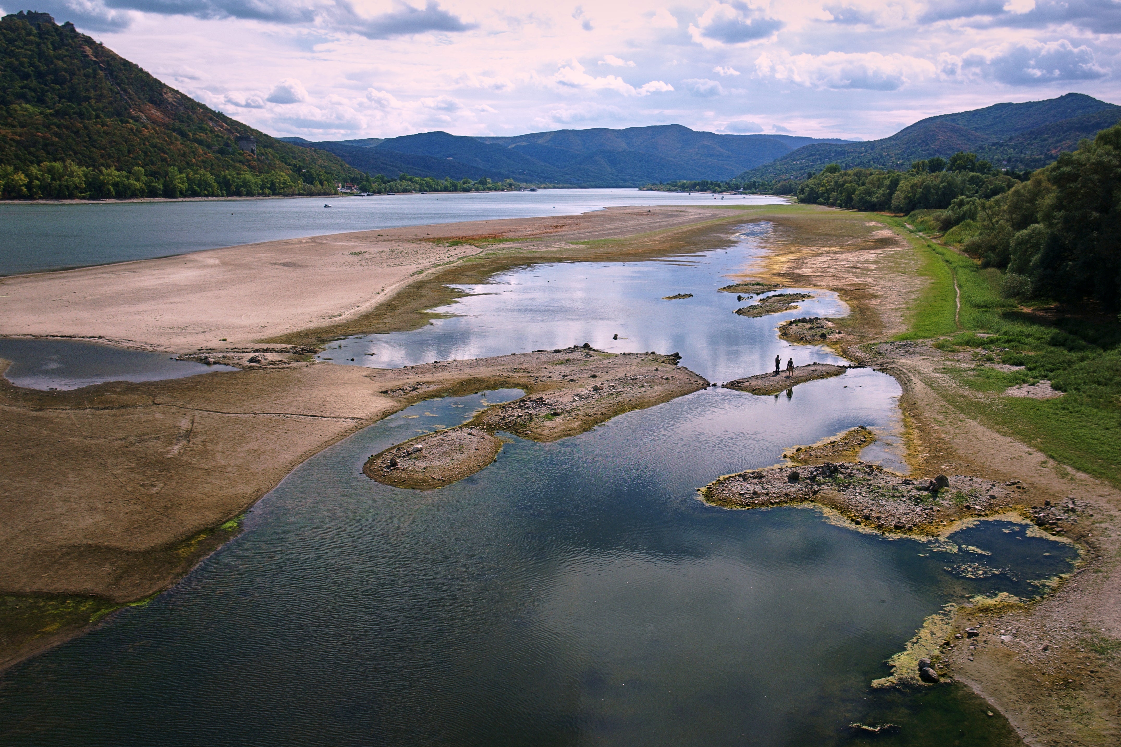 People walk on sandbanks exposed by record-low water levels in the Danube River after drought and extreme heat near Nagymaros, Hungary, on Aug. 18, 2026. (AP Photo/Bela Szandelszky)