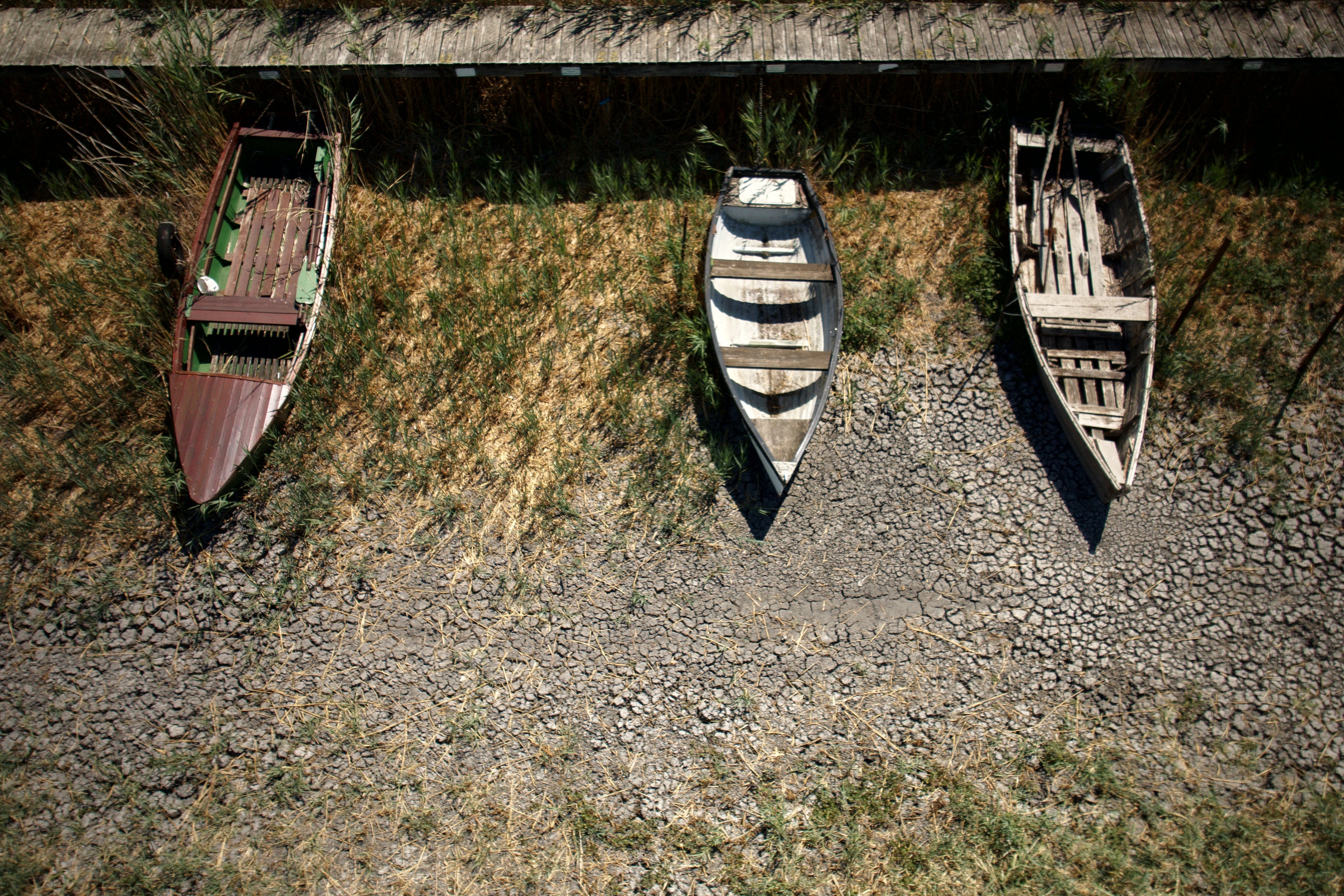 Boats lie on cracked soil at a dried-out marina on Lake Velence, Hungary, on Aug. 13. 2026. (AP Photo/Bela Szandelszky)