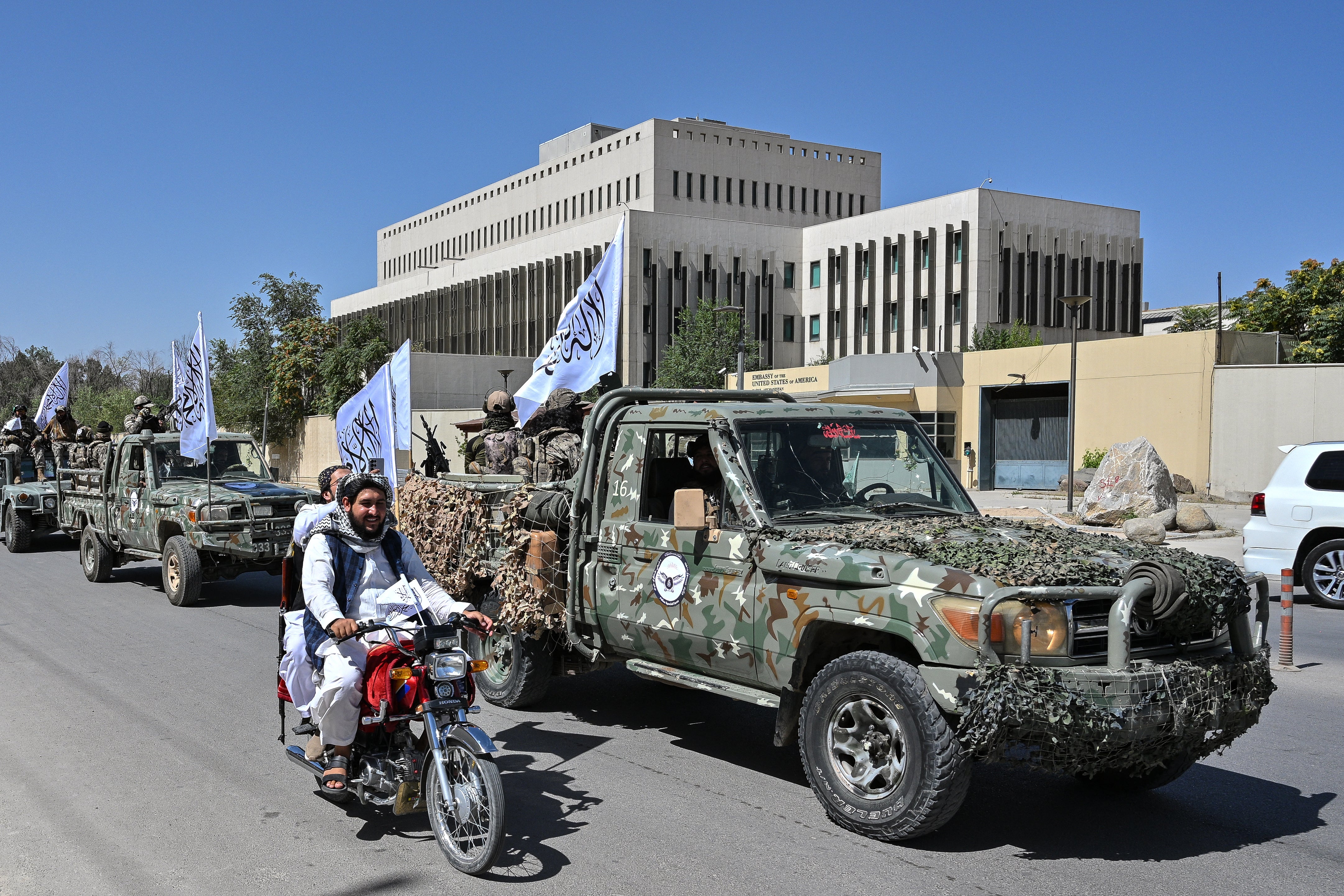 A convoy of Taliban security personnel take part in a parade in front of the former US Embassy building in Kabul