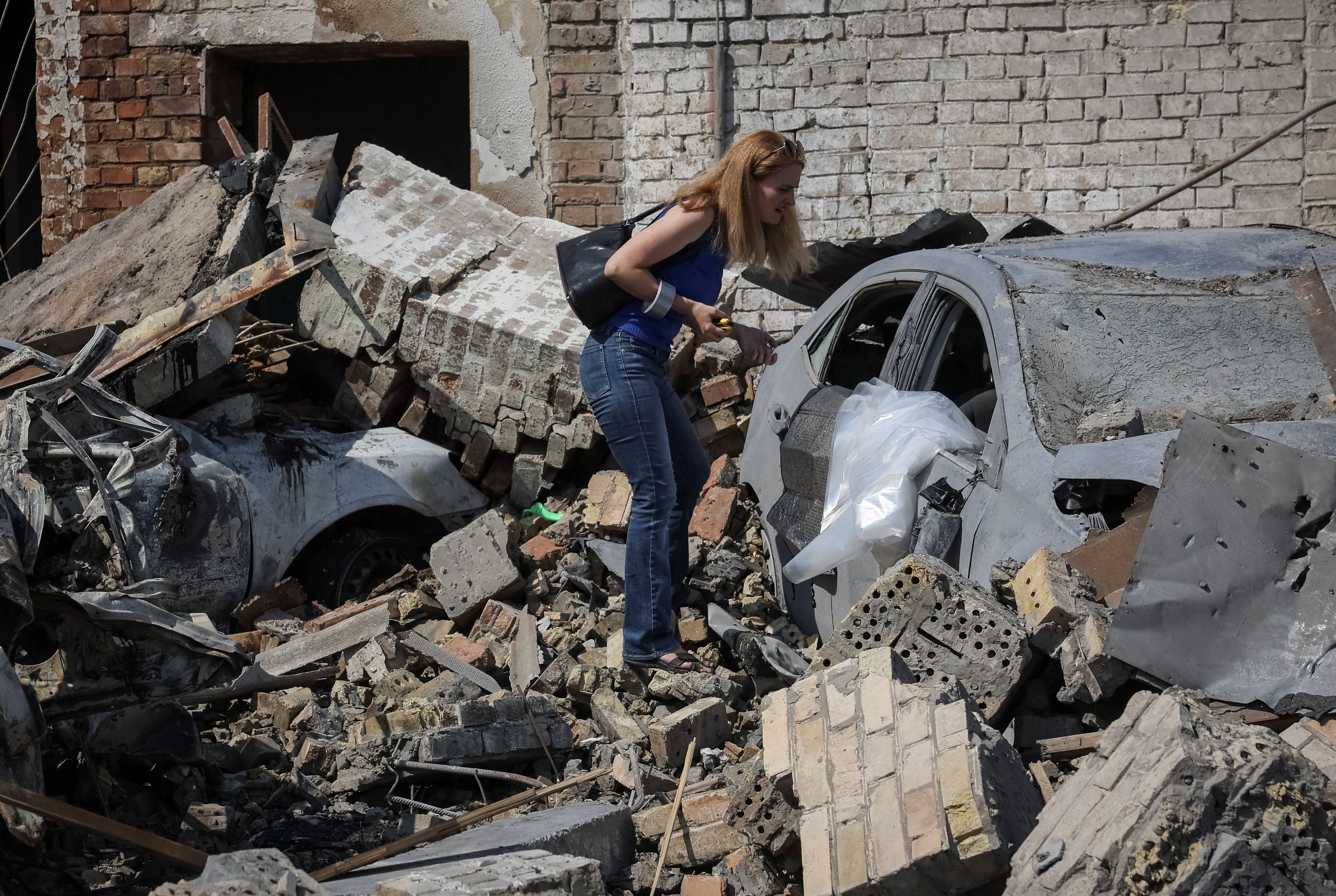 A woman inspects her destroyed car at a site of yesterday's missile strike, amid Russia's attack on Ukraine, in Kyiv, Ukraine, August 21, 2026. REUTERS/Gleb Garanich (Reuters)