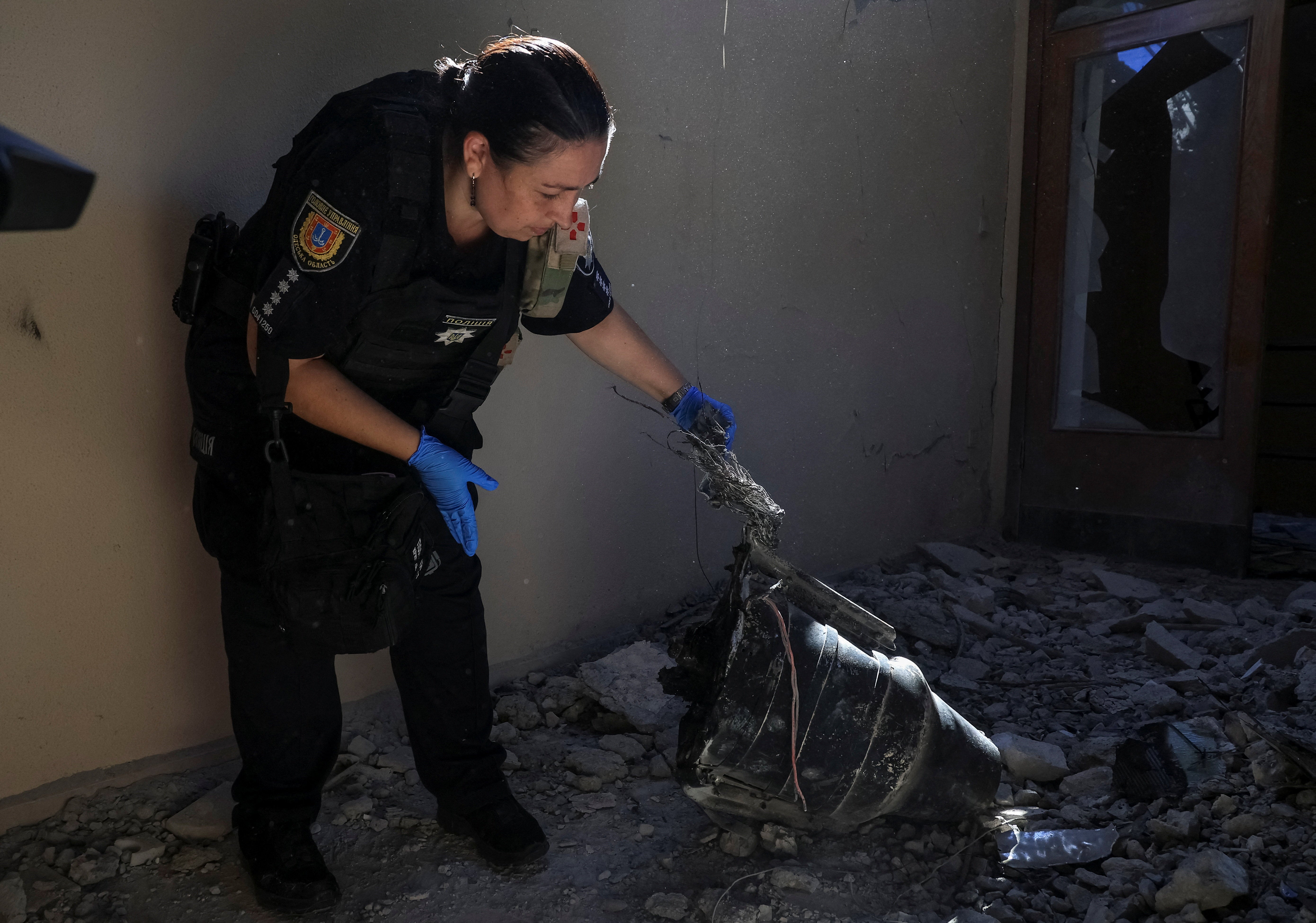 A police officer inspects a part of a Russian drone at a training base of the FC Chornomorets Odesa damaged during a Russian drone strike