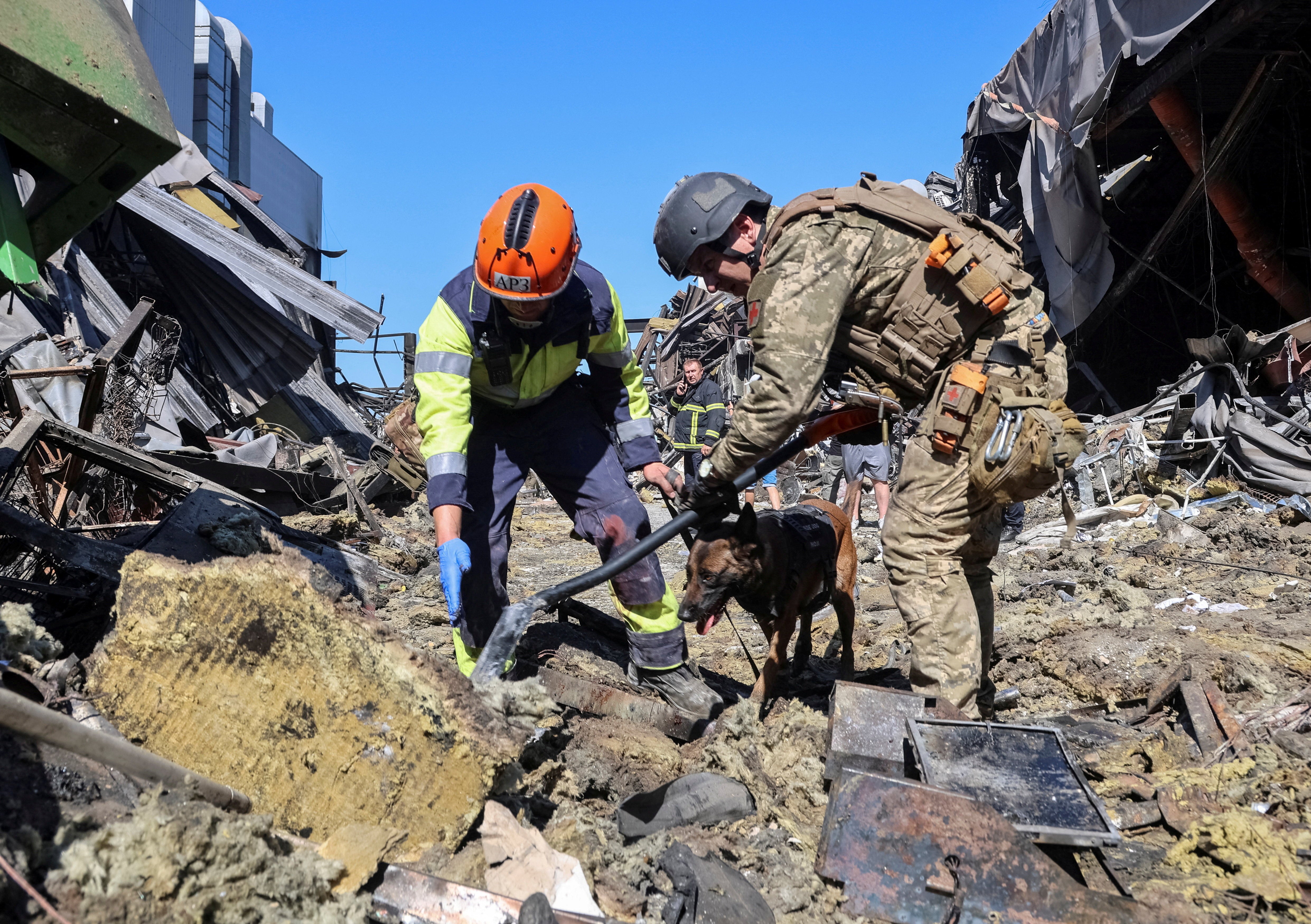 Rescuers with a dog work at a site of a shopping centre destroyed by yesterday's Russian drone attack
