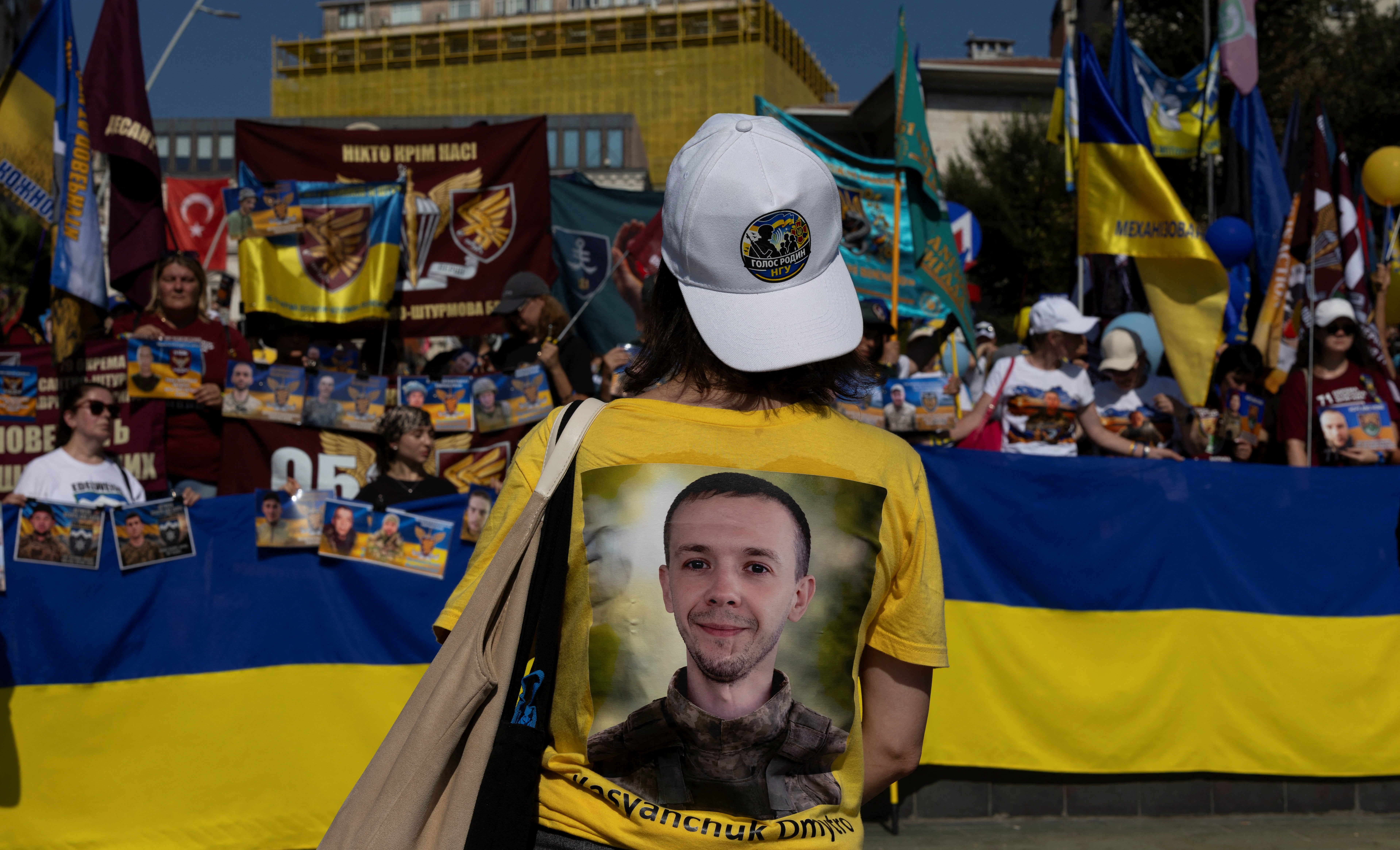 A Ukrainian woman wearing a T-shirt with a printed picture of a missing Ukrainian soldier on the back