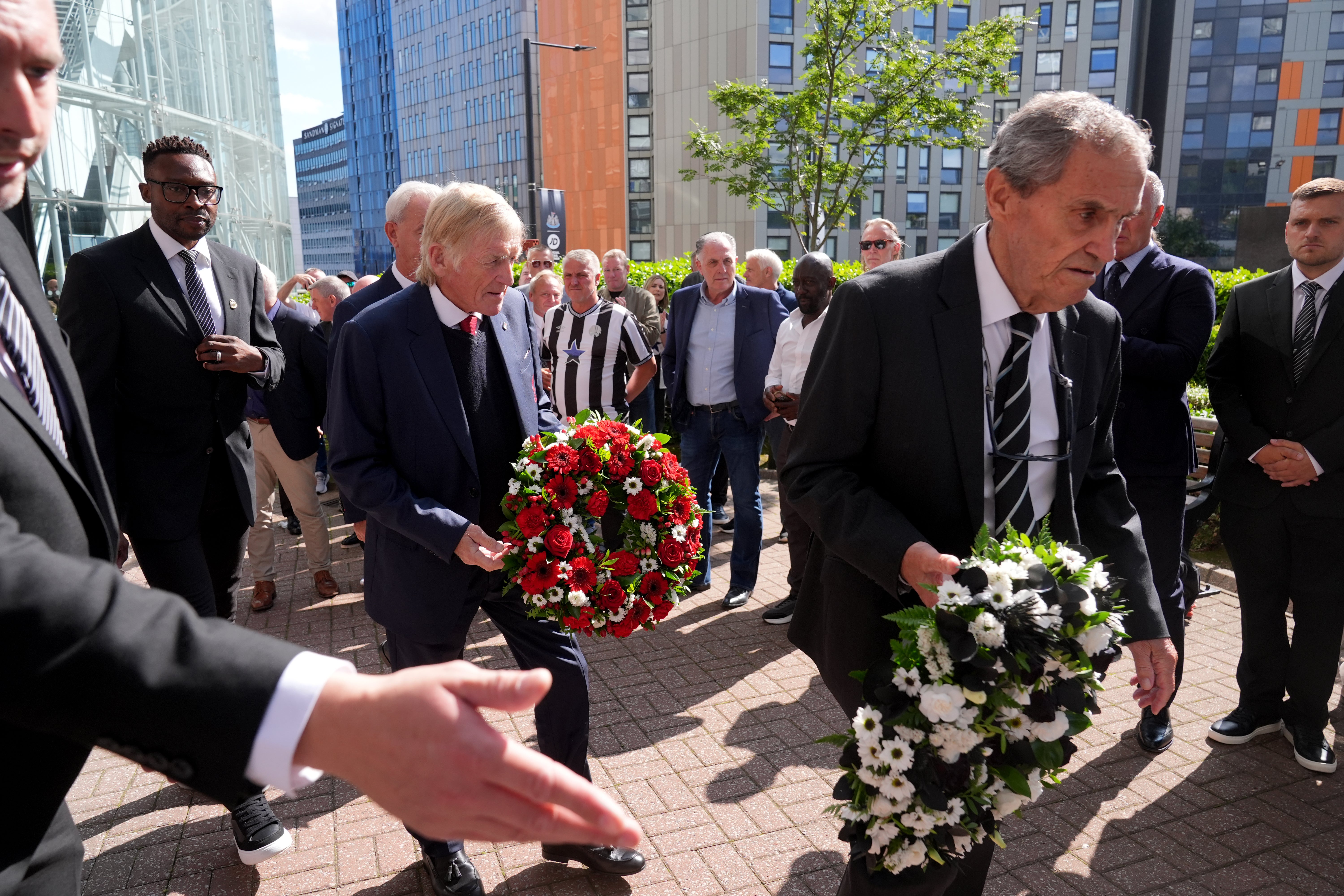 Kenny Dalglish, Shola Ameobi and Bobby Moncur (right) lay down a wreath of roses in memory of the late Kevin Keegan