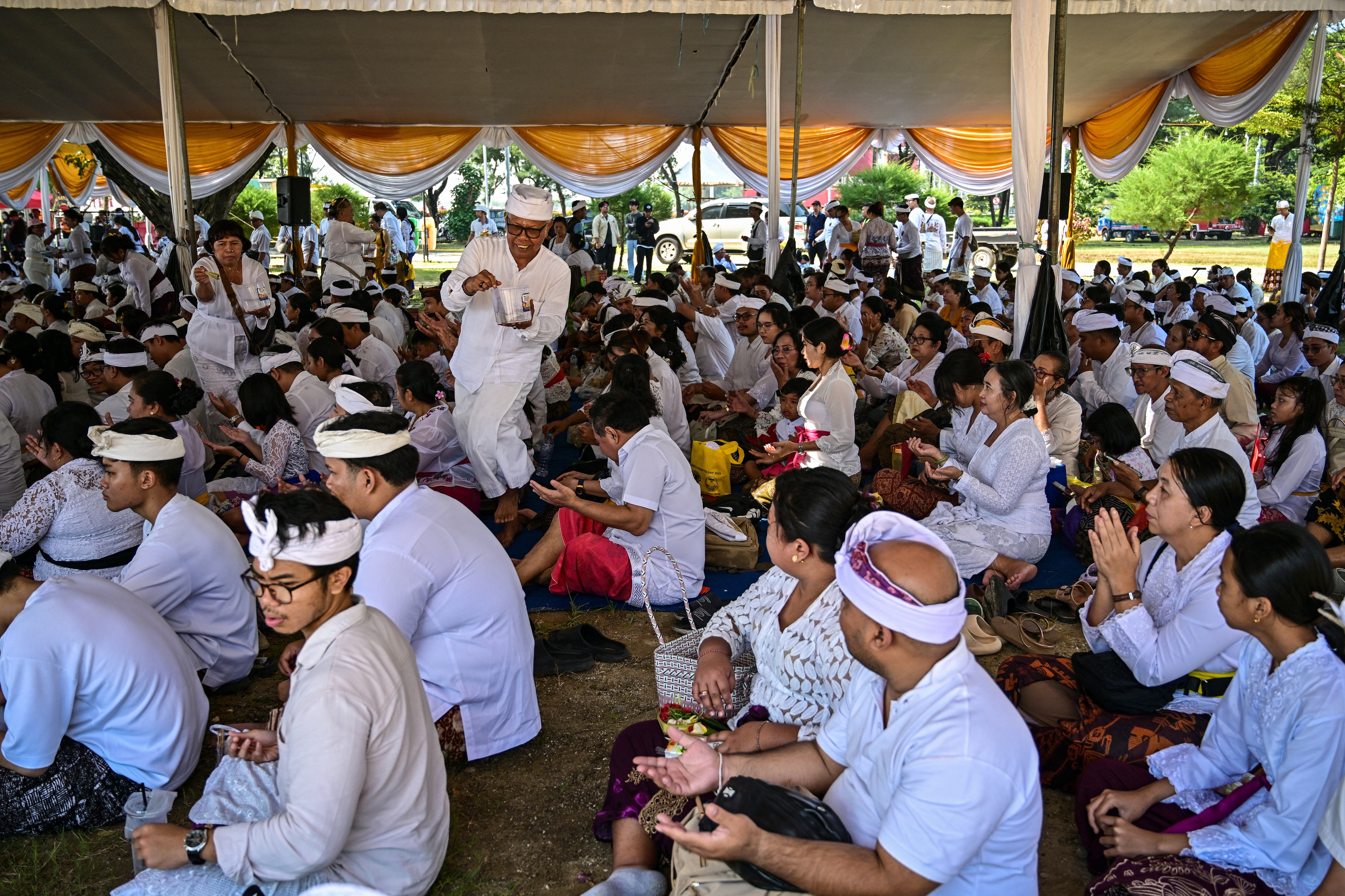 A Hindu priest sprinkles holy water over devotees during the Melasti ceremony prayer at Kenjeran beach in Surabaya on 14 March 2026