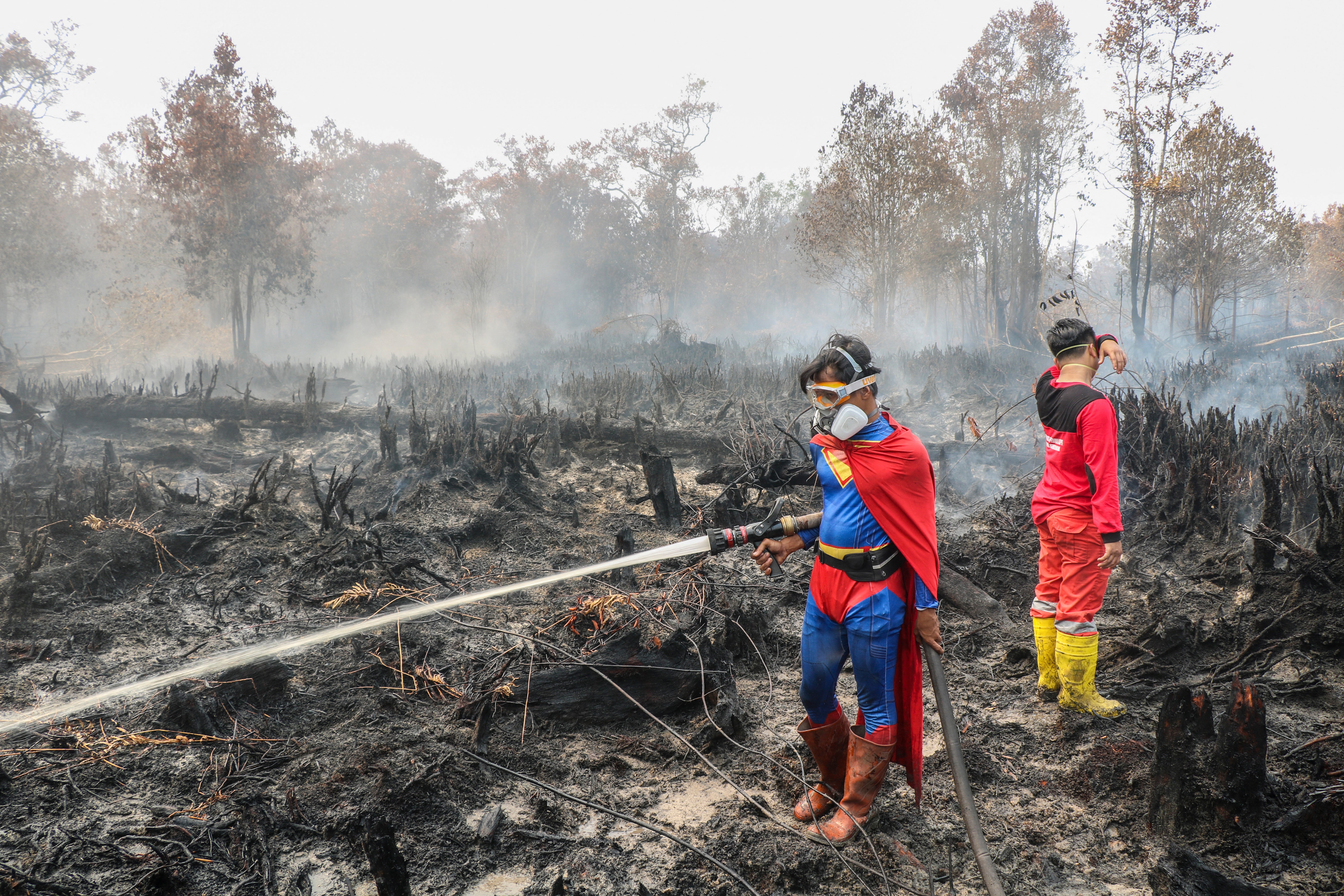 Student Rudiansyah (left) dressed in a Superman costume helps to extinguish a forest and land fire at Petuk Katimpun in Palangkaray, Indonesia (AFP/Getty)
