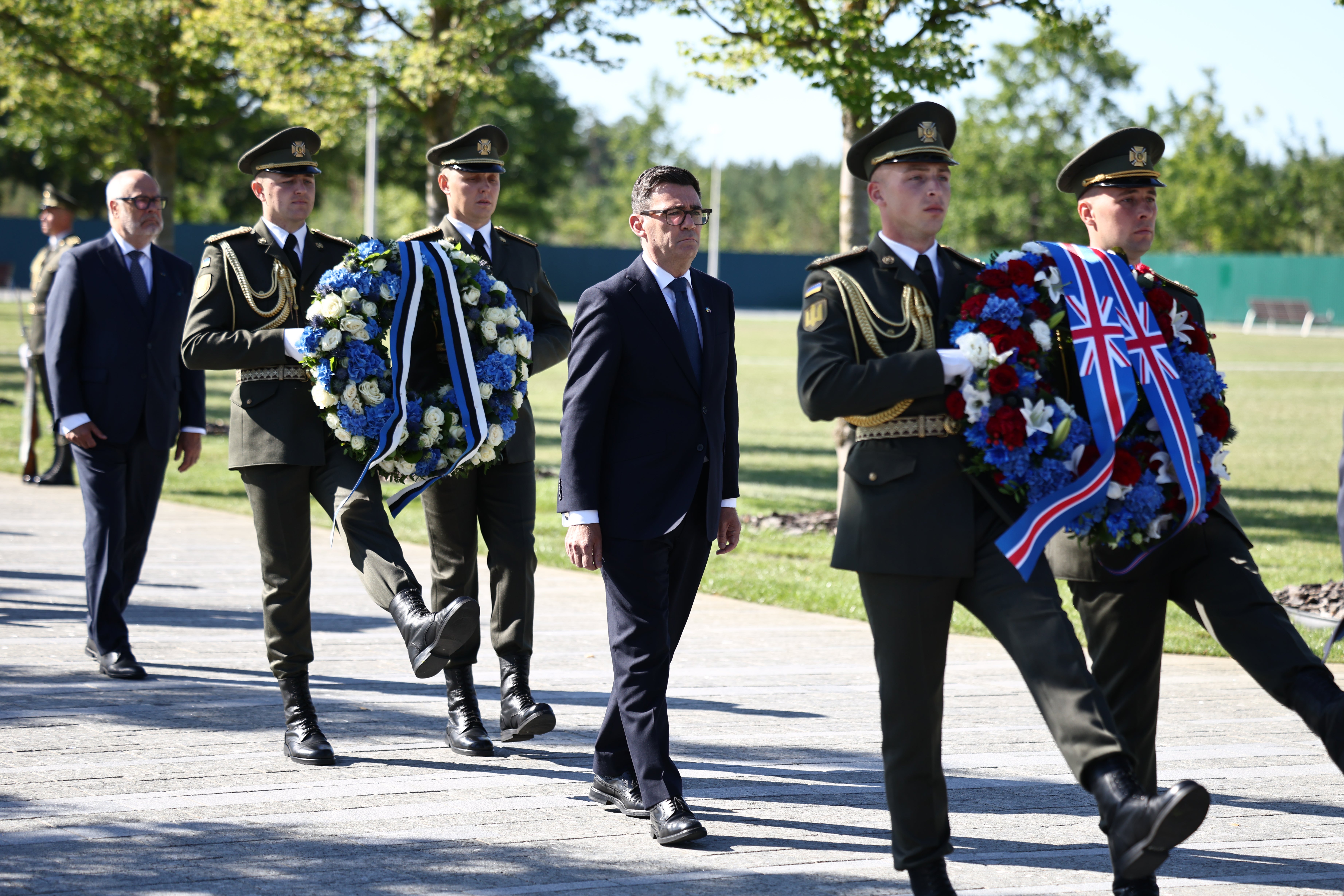 Britain's prime minister Andy Burnham (C) and Estonia's President Alar Karis (L) take part in a wreath-laying ceremony at Ukraine's national military memorial cemetery