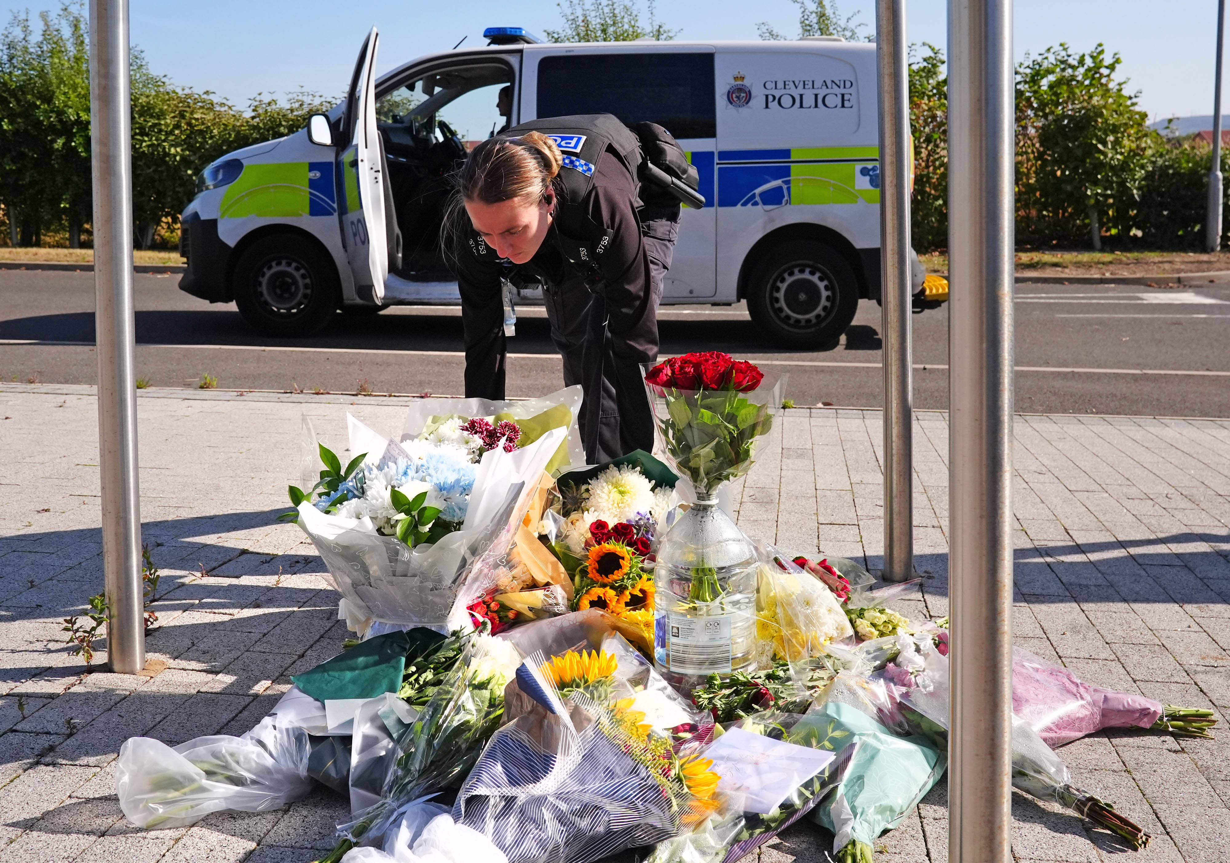 A police officer leaves flowers at the Cleveland Police HQ Memorial Garden in Middlesbrough, following the line-of-duty deaths of PC Matthew Blades and PC Tom Clough
