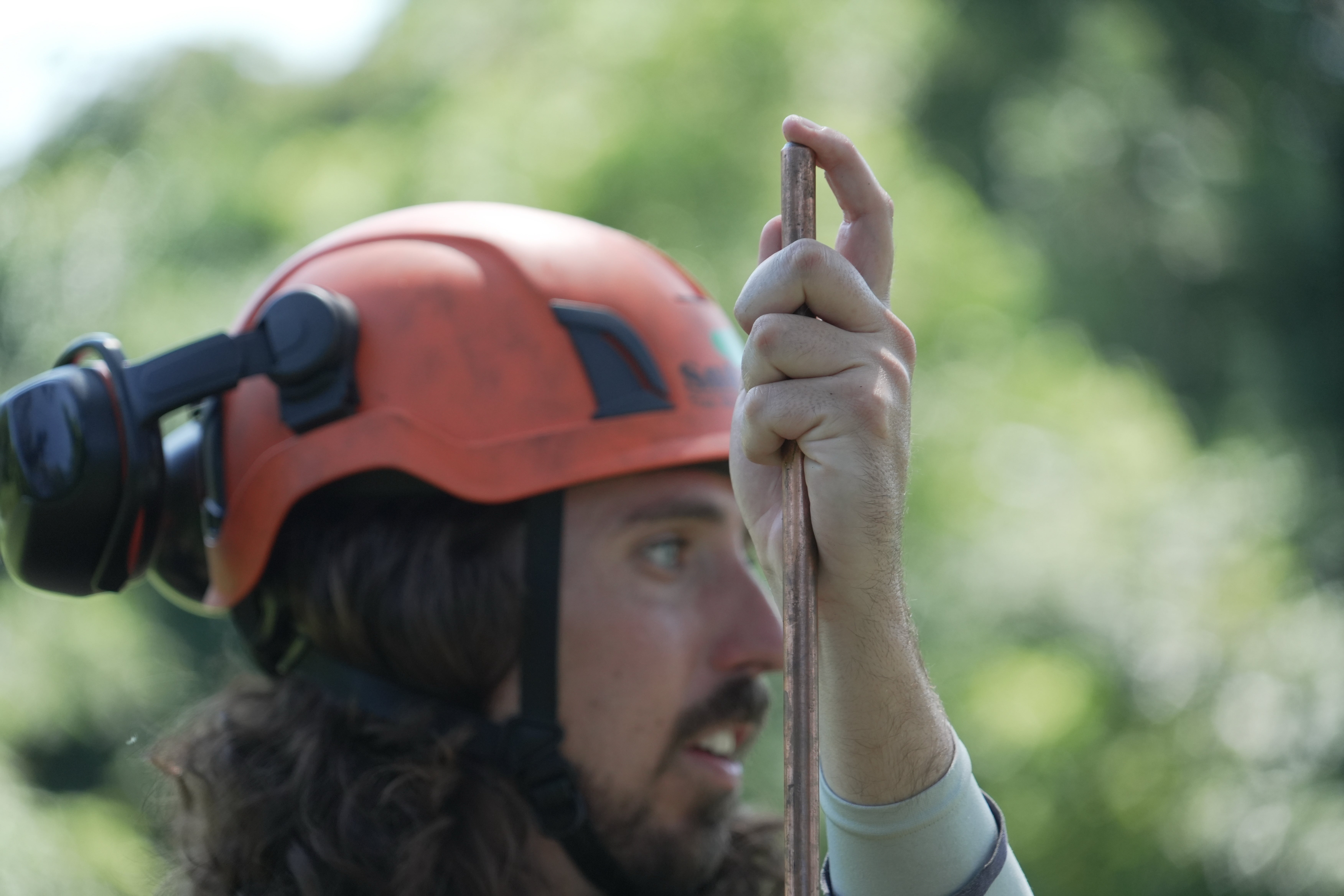 Commercial arborist Jake Love of SavATree holds a copper lightning rod next to the tree