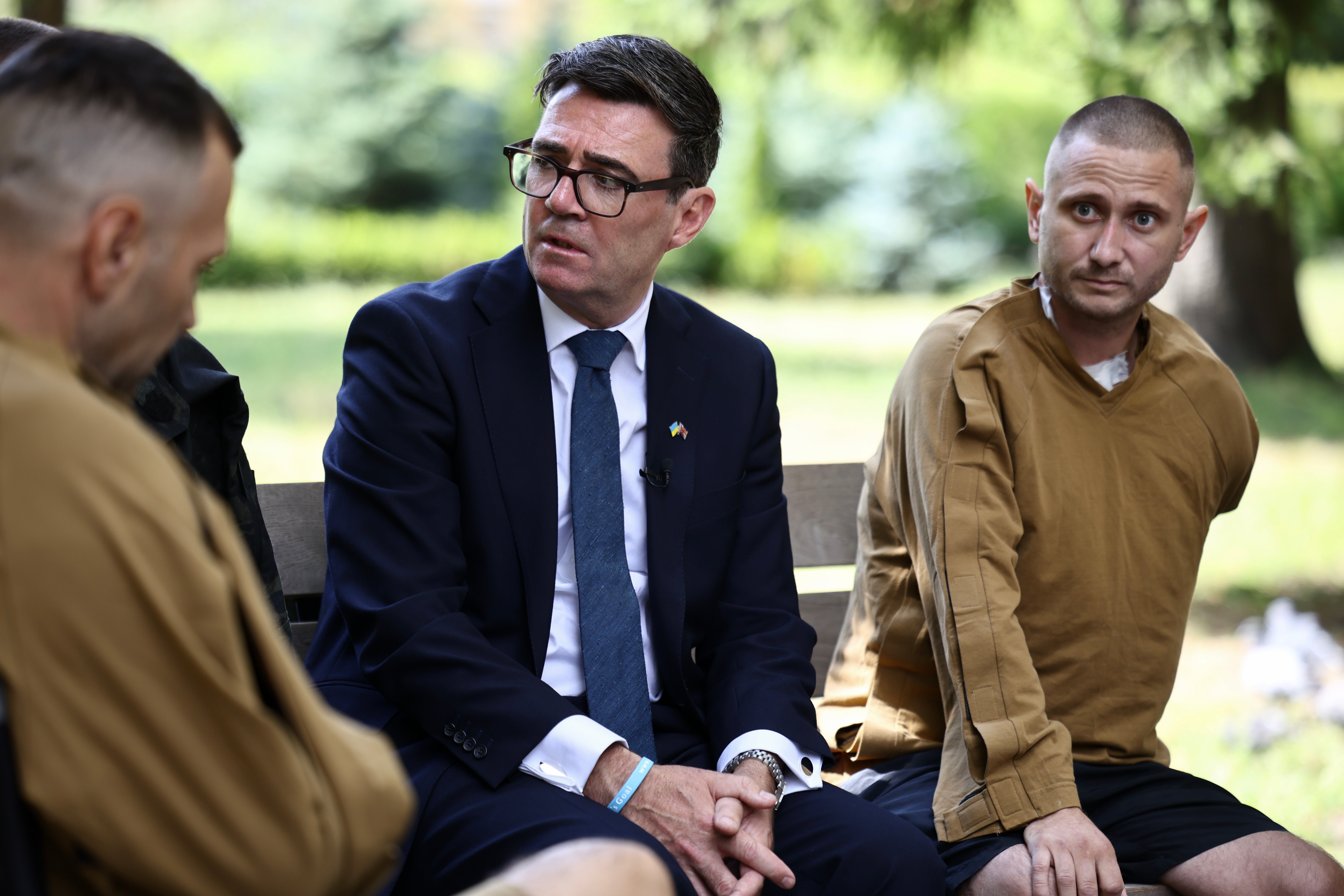 Britain's prime minister Andy Burnham (C) gestures as he meets patients wounded in the war at the Main Military Hospital