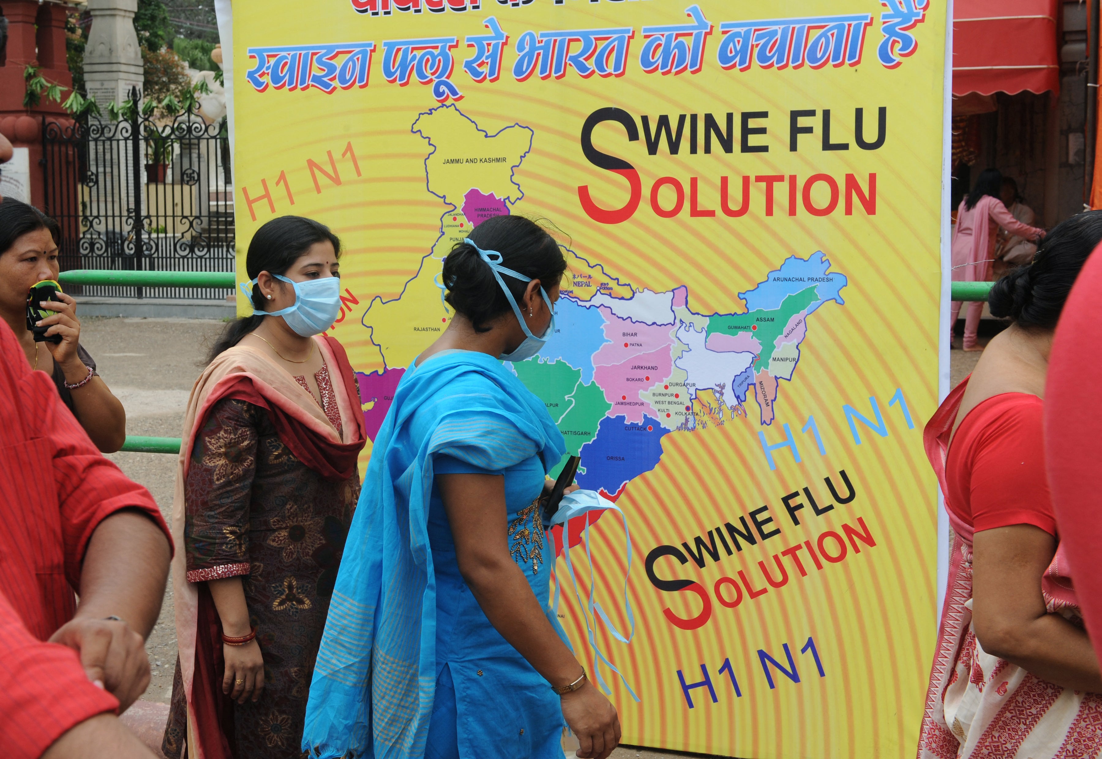 Indian women wear masks to prevent swine flu infection as they queue up at a temple to pray during the 'Janmashtami' festival in Delhi on 14 August 2009