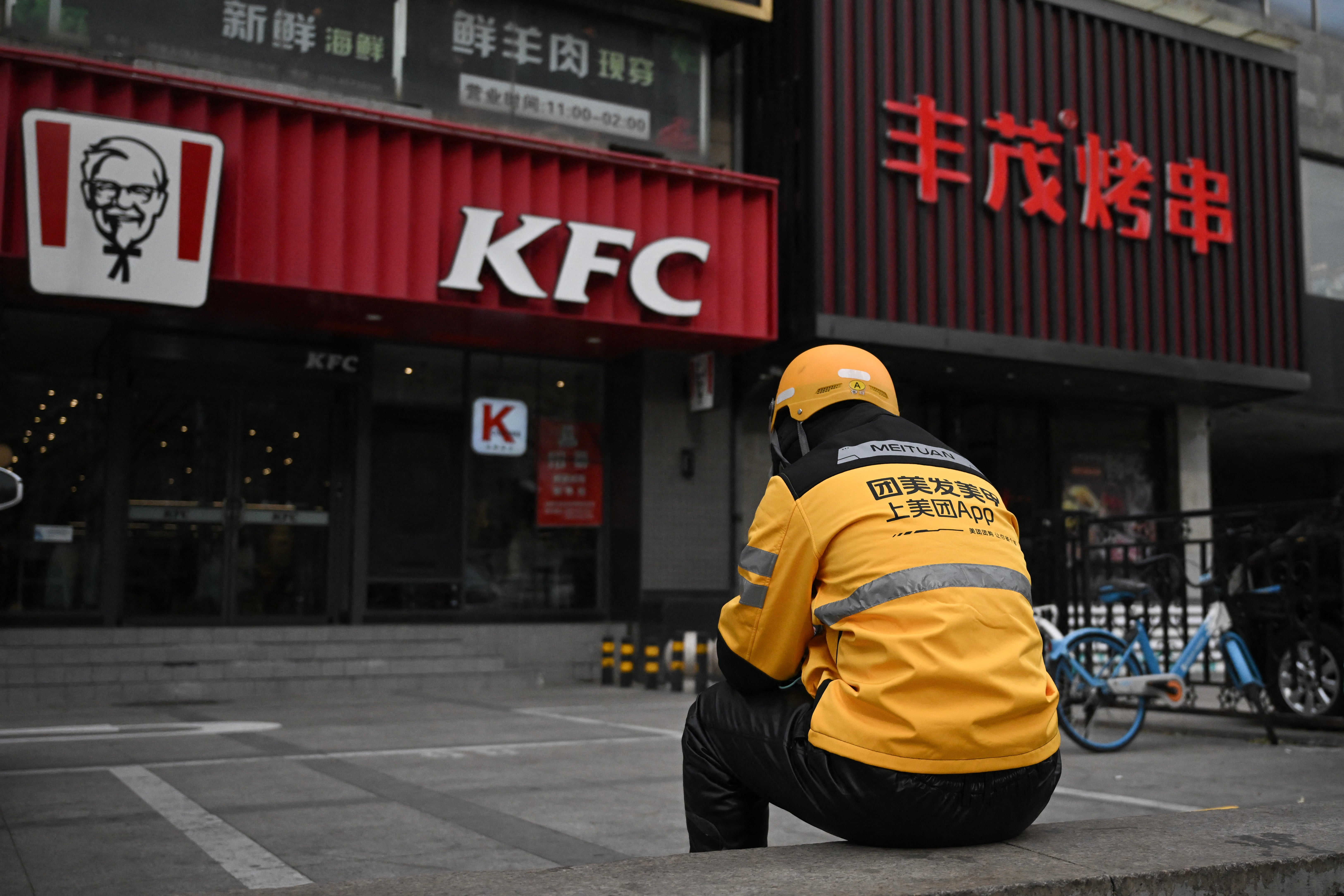 A food delivery person for Meituan waits for orders outside a KFC outlet in Beijing (AFP/Getty)