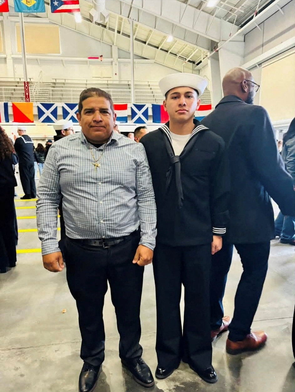 Joshua Aviles, a U.S. sailor deployed in the Middle East during the Iran war, stands next to his father, who was taken into federal immigration detention
