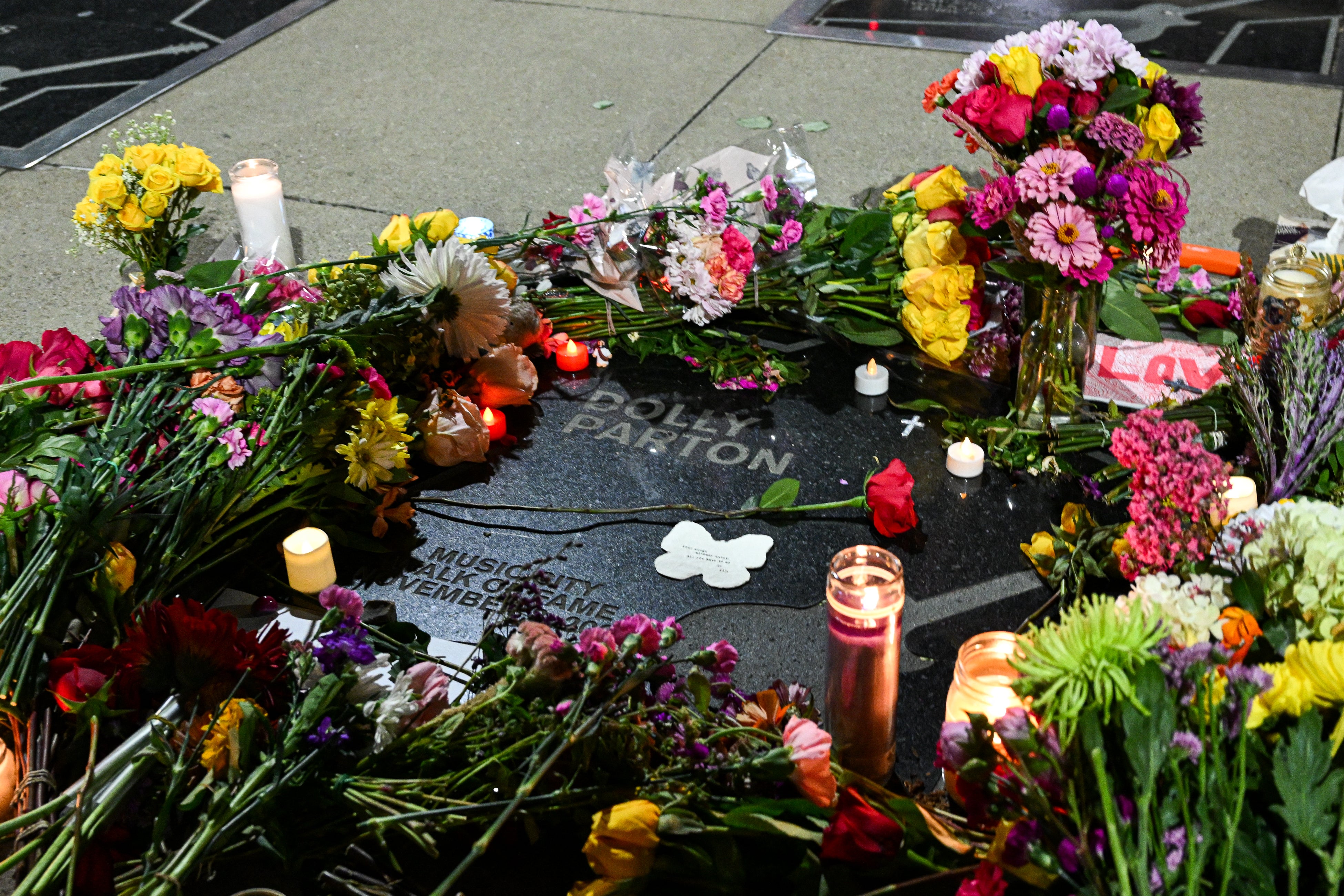 Flowers and candles, placed by fans, cover Dolly Parton's star on The Music City Walk of Fame in Nashville, Tennessee
