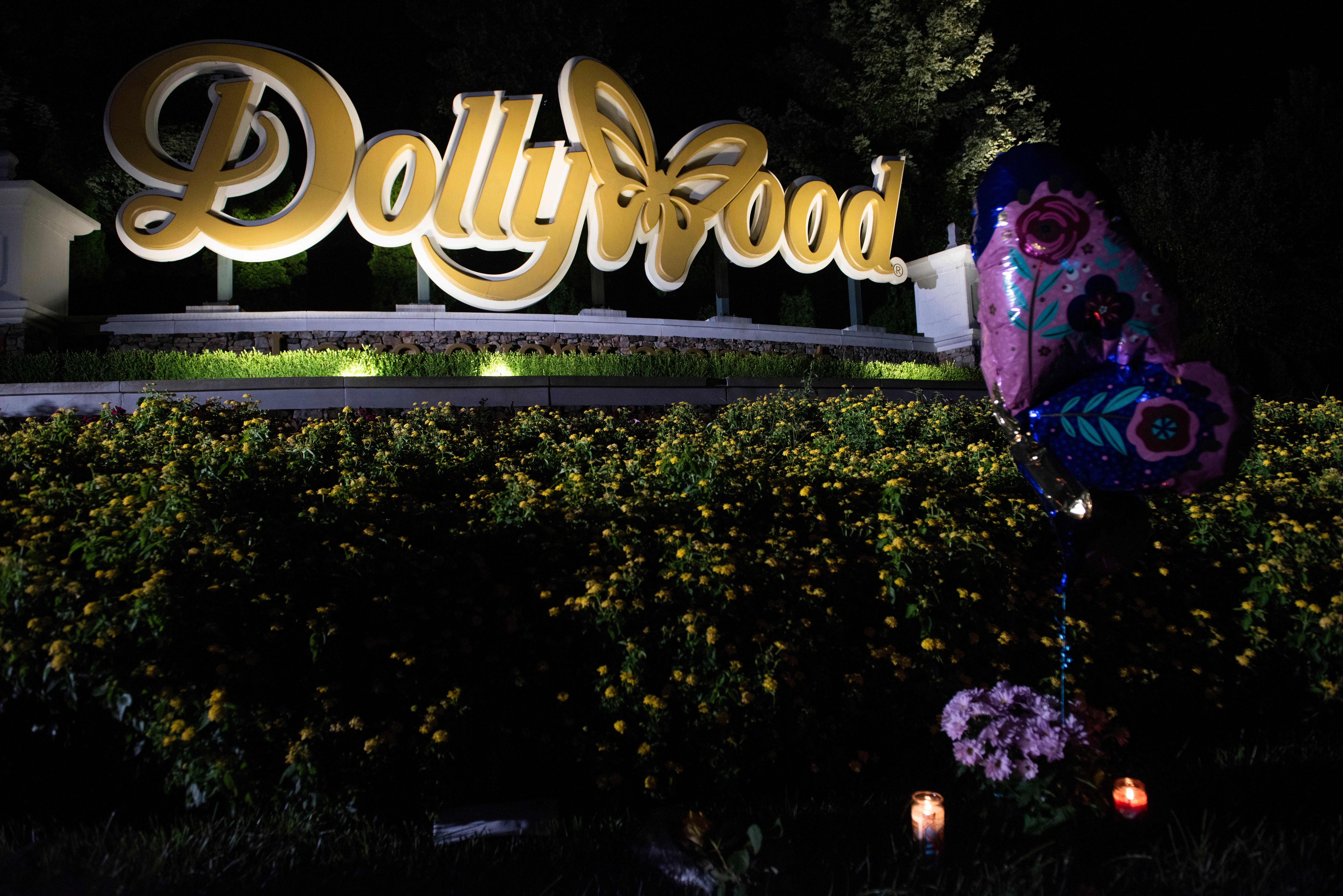 The sign for Dollywood, the theme park started by Dolly Parton in 1961, is lit up at night amid a few momentos left by fans in Pigeon Forge, Tennessee