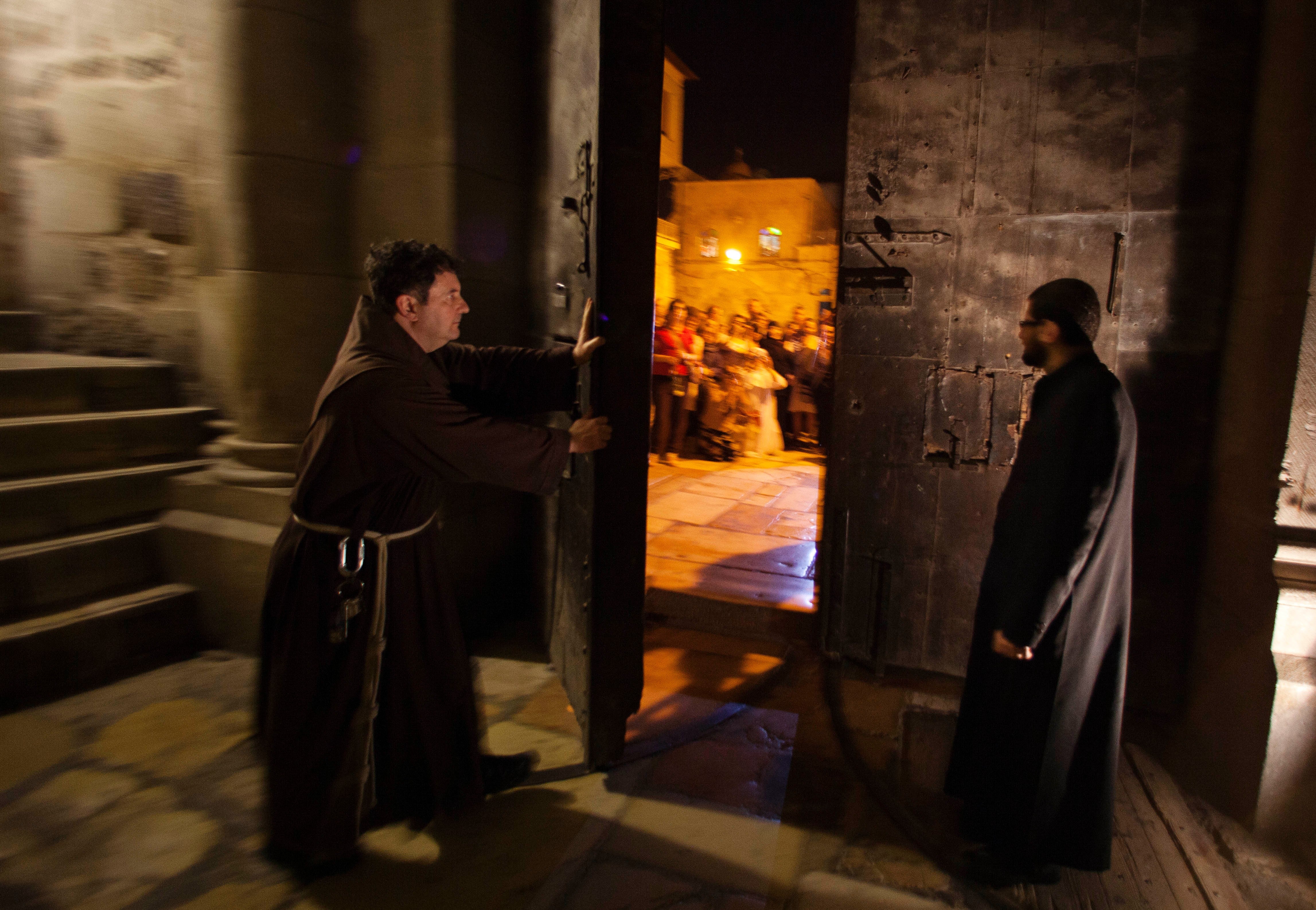 A priest closes the door to the Holy Sepulcher church for the night in Jerusalem