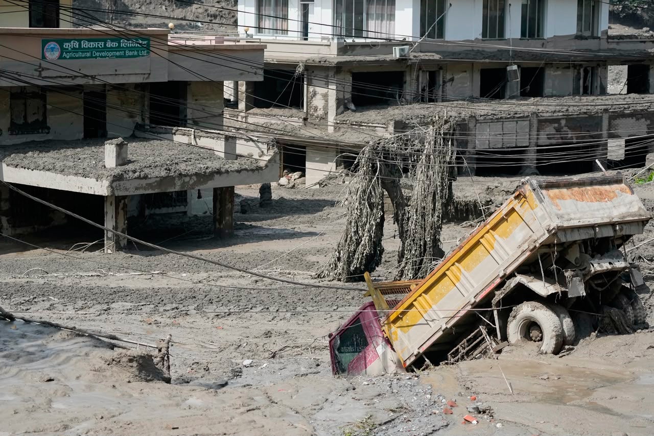 Houses and vehicles damaged after the flash floods from the river Rishuli in the district of Nuwakot, Nepal, on Wednesday (AP)