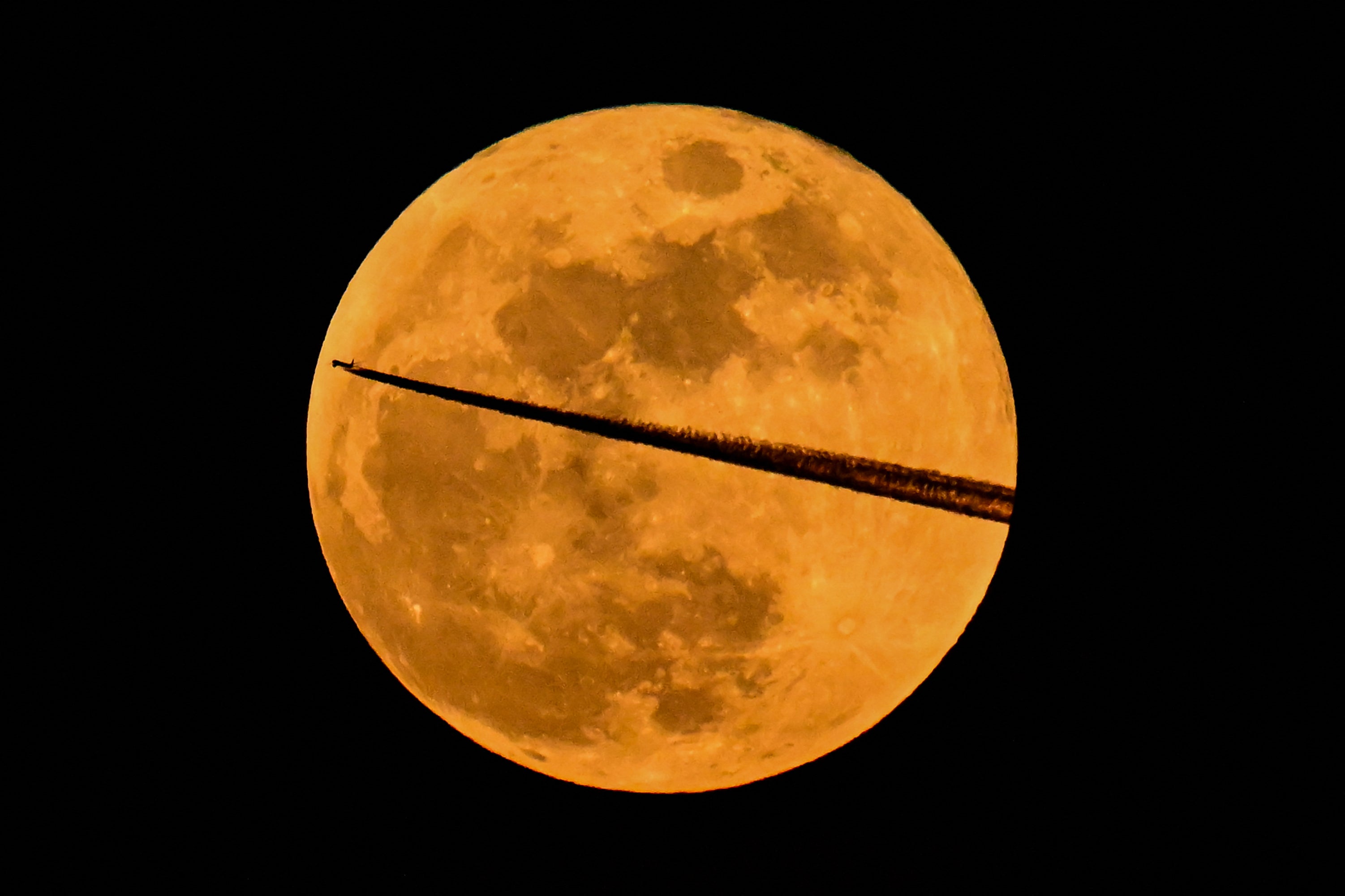 A Bulgaria Air Airbus A220-100 aircraft flies past the March full moon, also known as the ‘Blood Moon’, in March