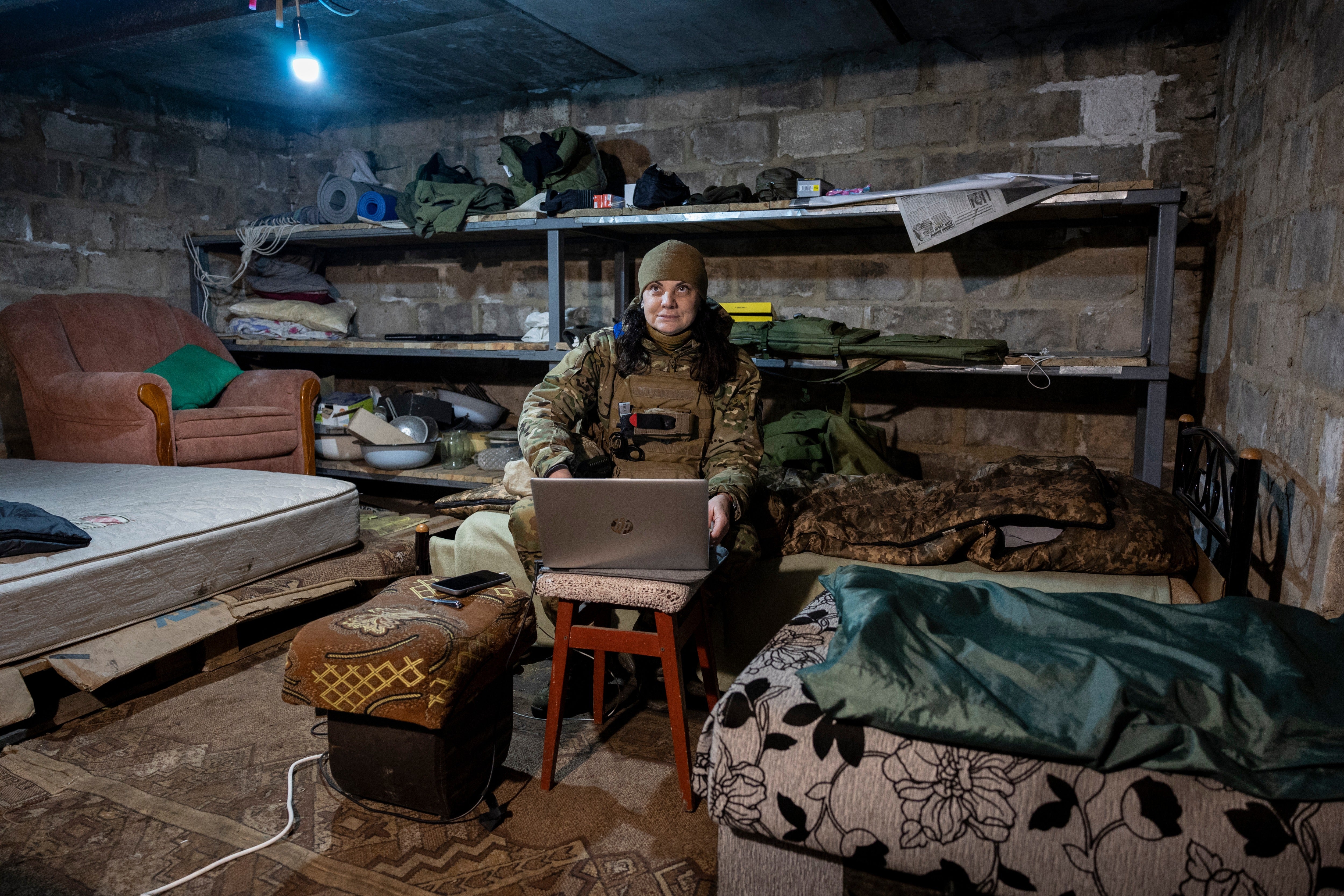 A Ukrainian frontline paramedic uses a Starlink internet connection in a basement living quarters as Russian shells nearby above ground on February 20, 2023 in the Donbas region of eastern Ukraine
