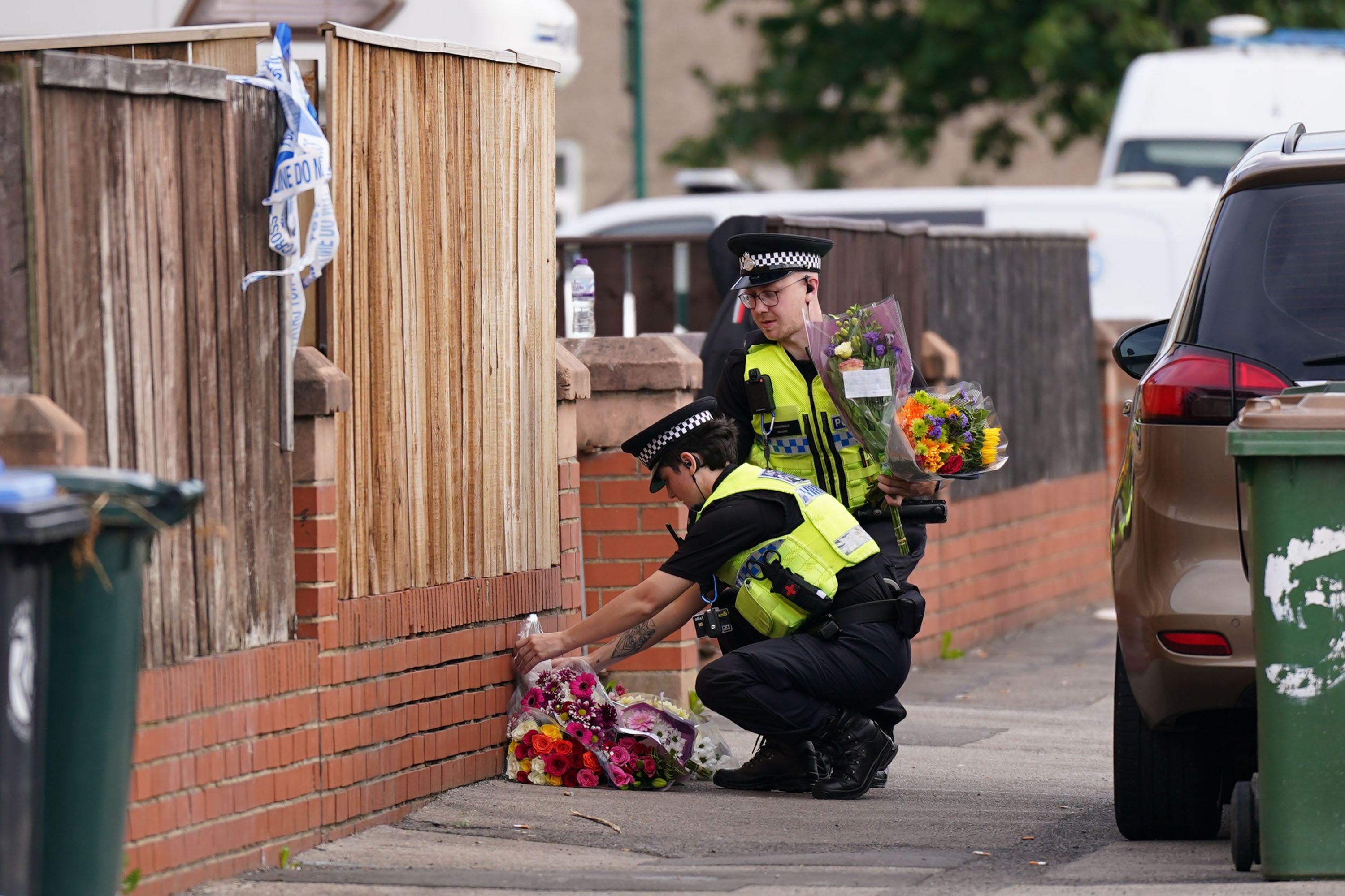Police lay flowers and tributes at the house