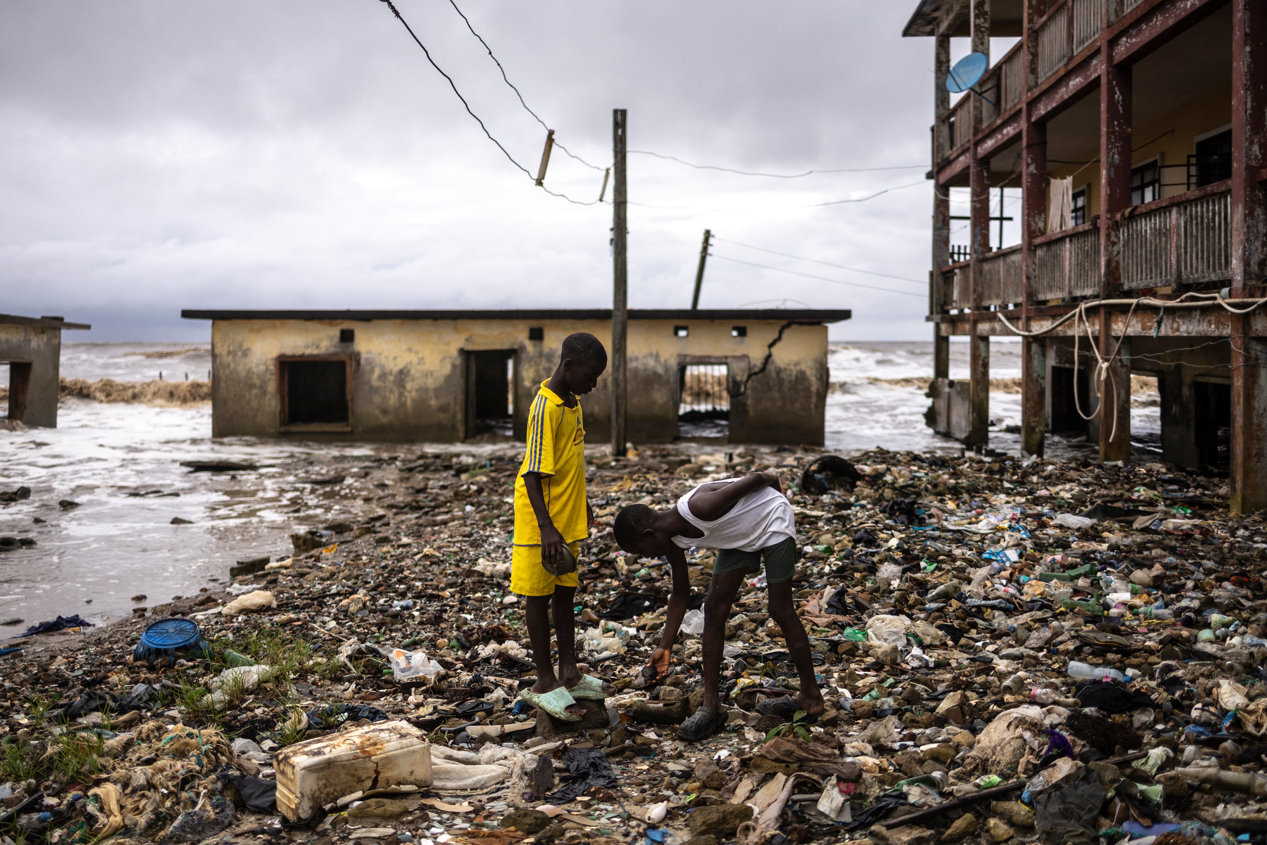 Children inspect debris washed ashore in Ayetoro, in Nigeria's Ondo State, where coastal erosion since the 2000s has gradually swallowed homes, schools, and other infrastructure