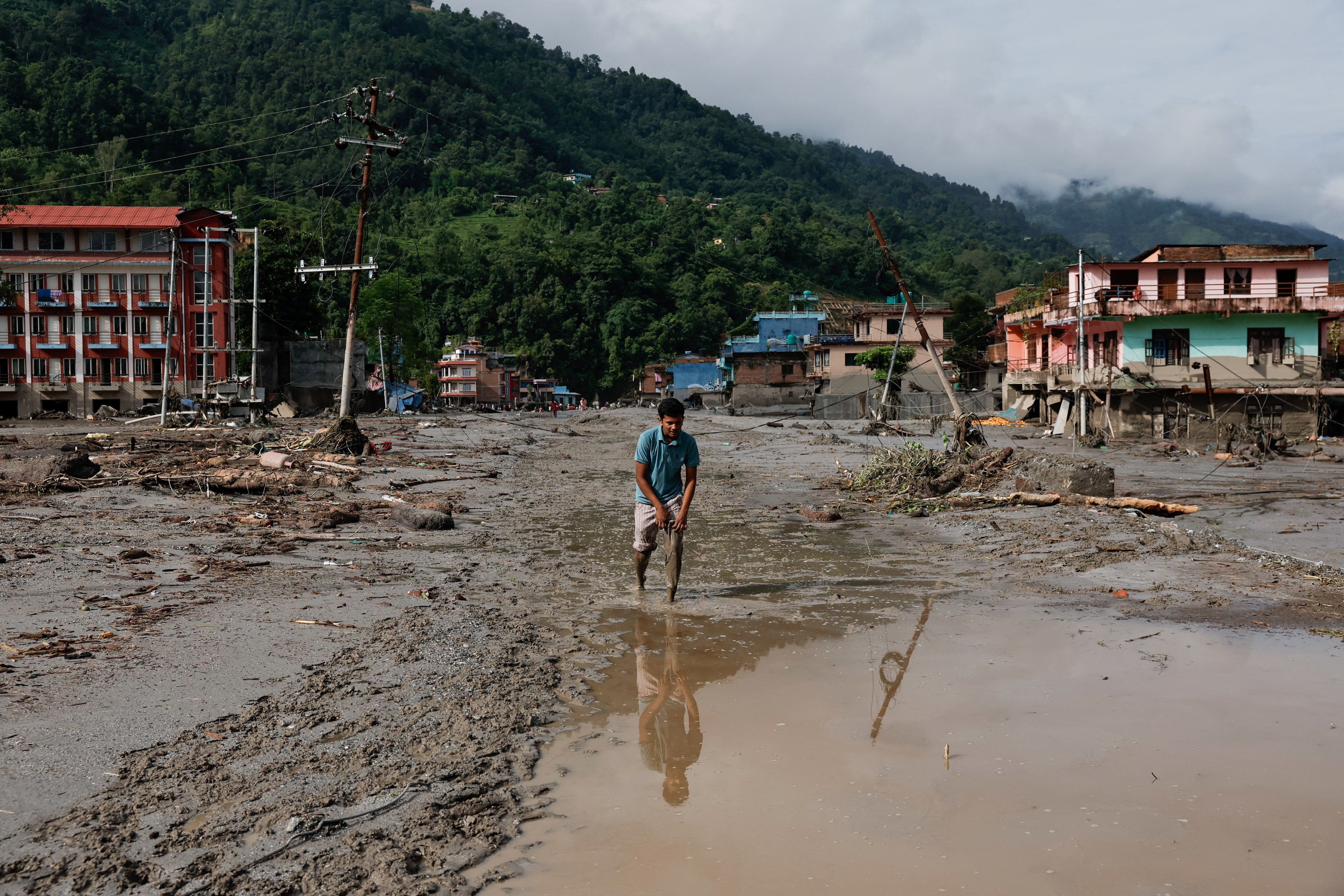 A man wades through muddy waters following devastating floods, in Trishuli in Nuwakot district, Nepal, August 27, 2026