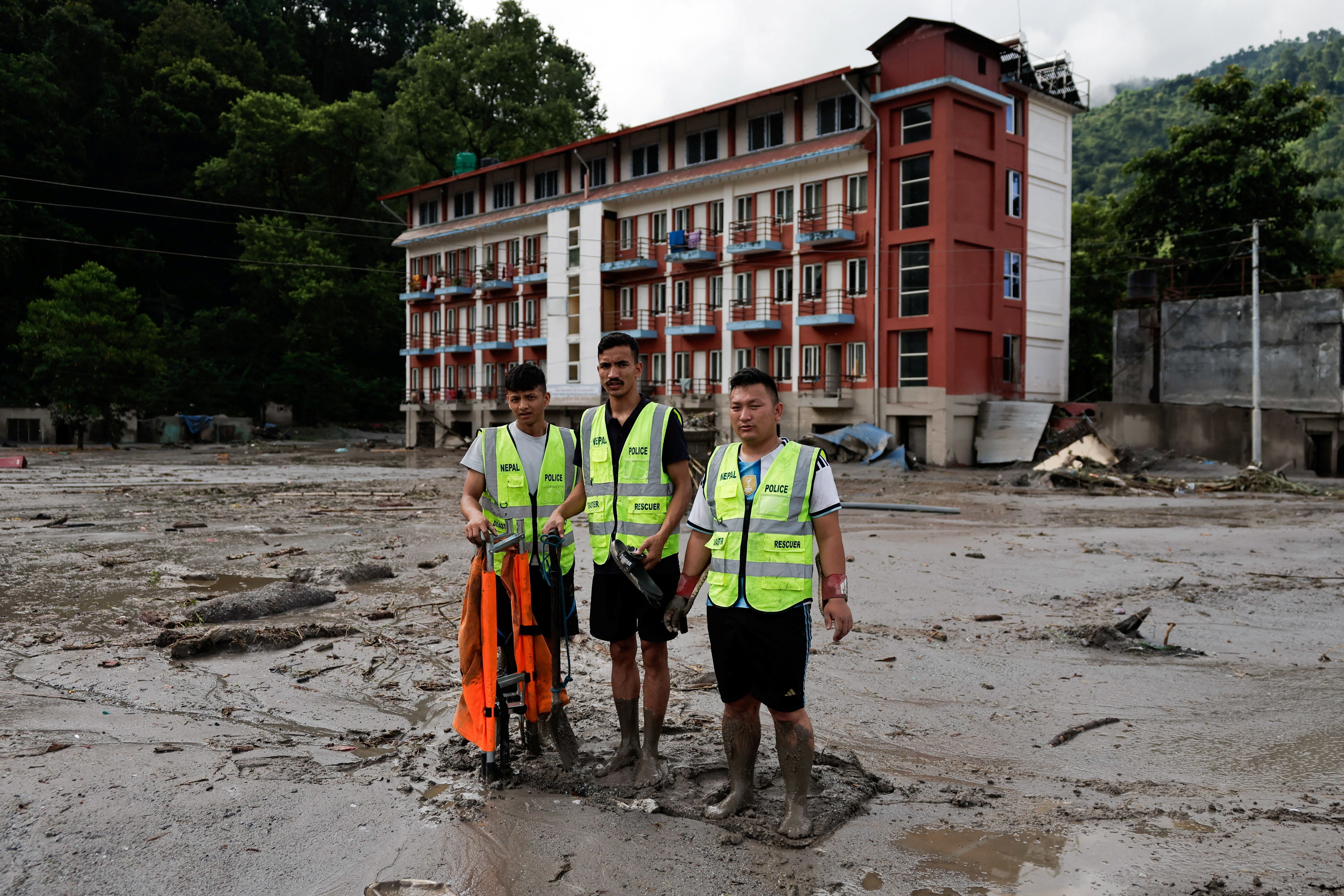 Members of a rescue team stand amid mud and debris following devastating floods, in Trishuli in Nuwakot district, Nepal, 27 August 2026