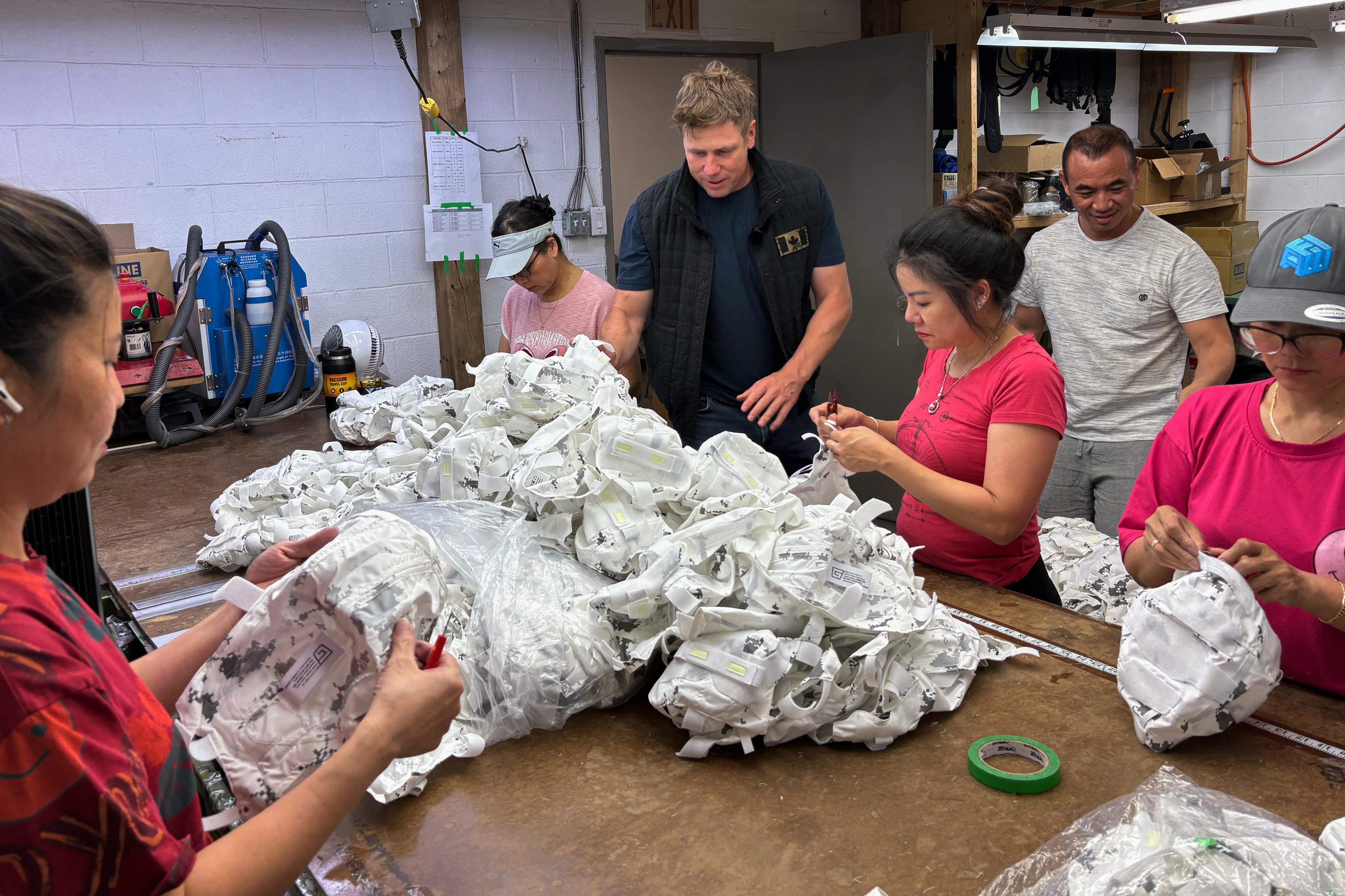 Wuxly CEO James Yurichuk and garment factory owner Aaron Lyand inspect military helmet covers on July 20, 2026, in North York, Ontario