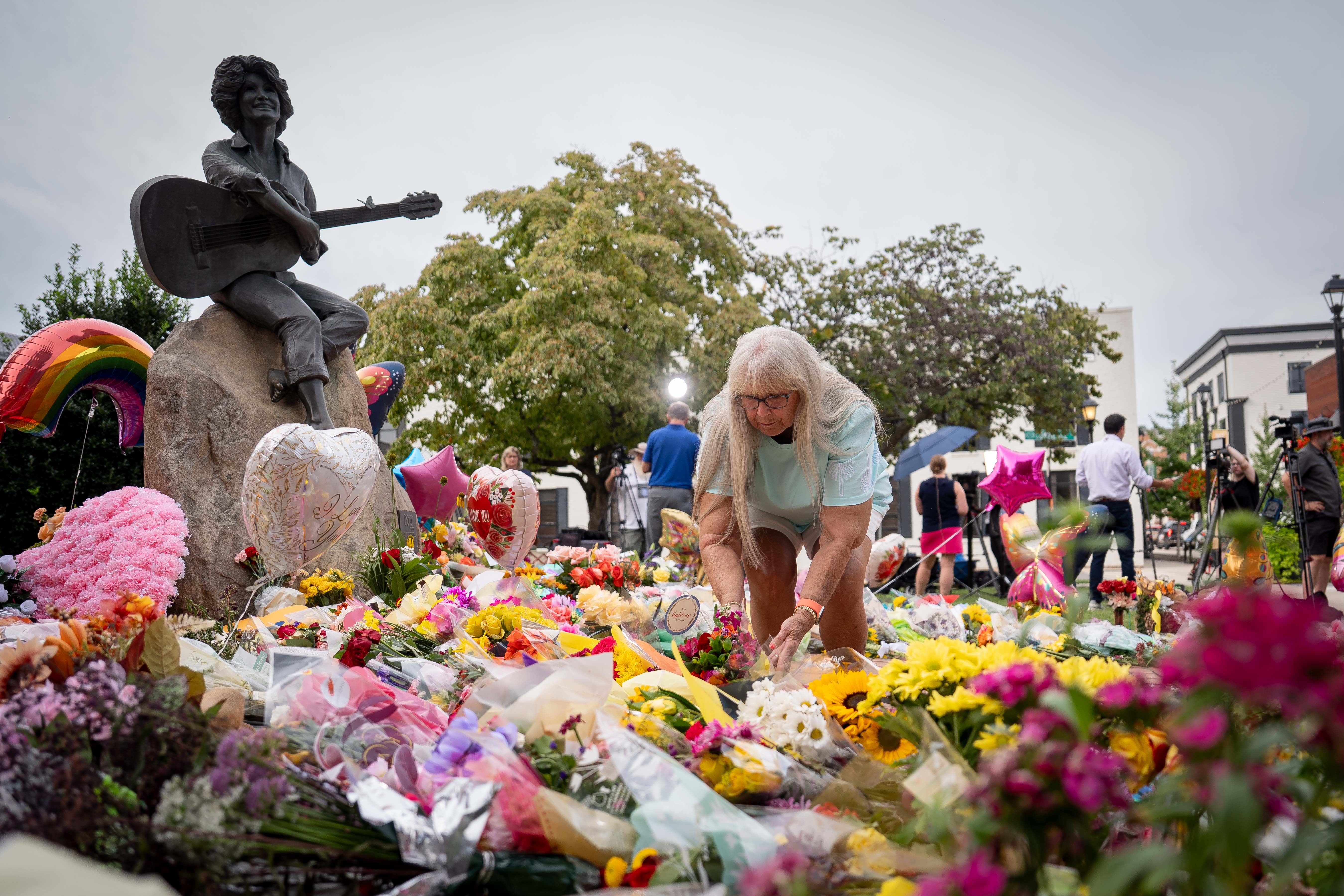 People lay flowers at a memorial honoring Dolly Parton in Sevierville, Tennessee (AP)