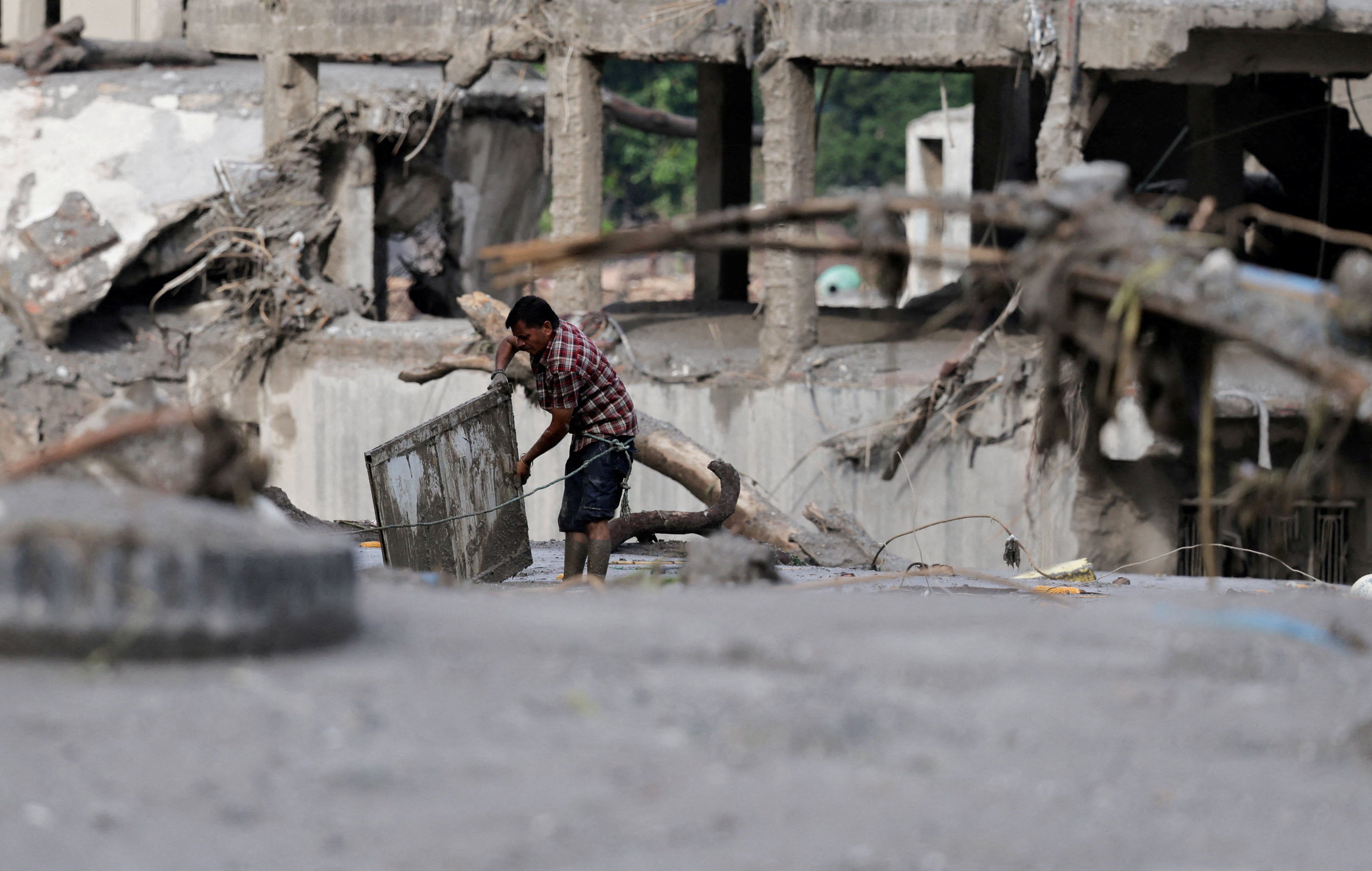 A man salvages his belongings from mud following devastating floods, in Trishuli in Nuwakot district, Nepal, August 27, 2026