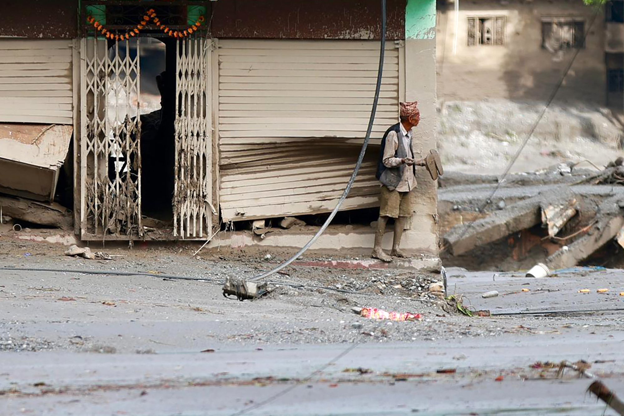 A local resident stands along a street lying deluged in sludge after flash floods near Devighat, Bidur Municipality in Nepal's Nuwakot district on August 27, 2026. Nepal's disaster agency said that 823 people remained out of contact on August 27, more than 24 hours after a deadly flood tore through the border region with Tibet