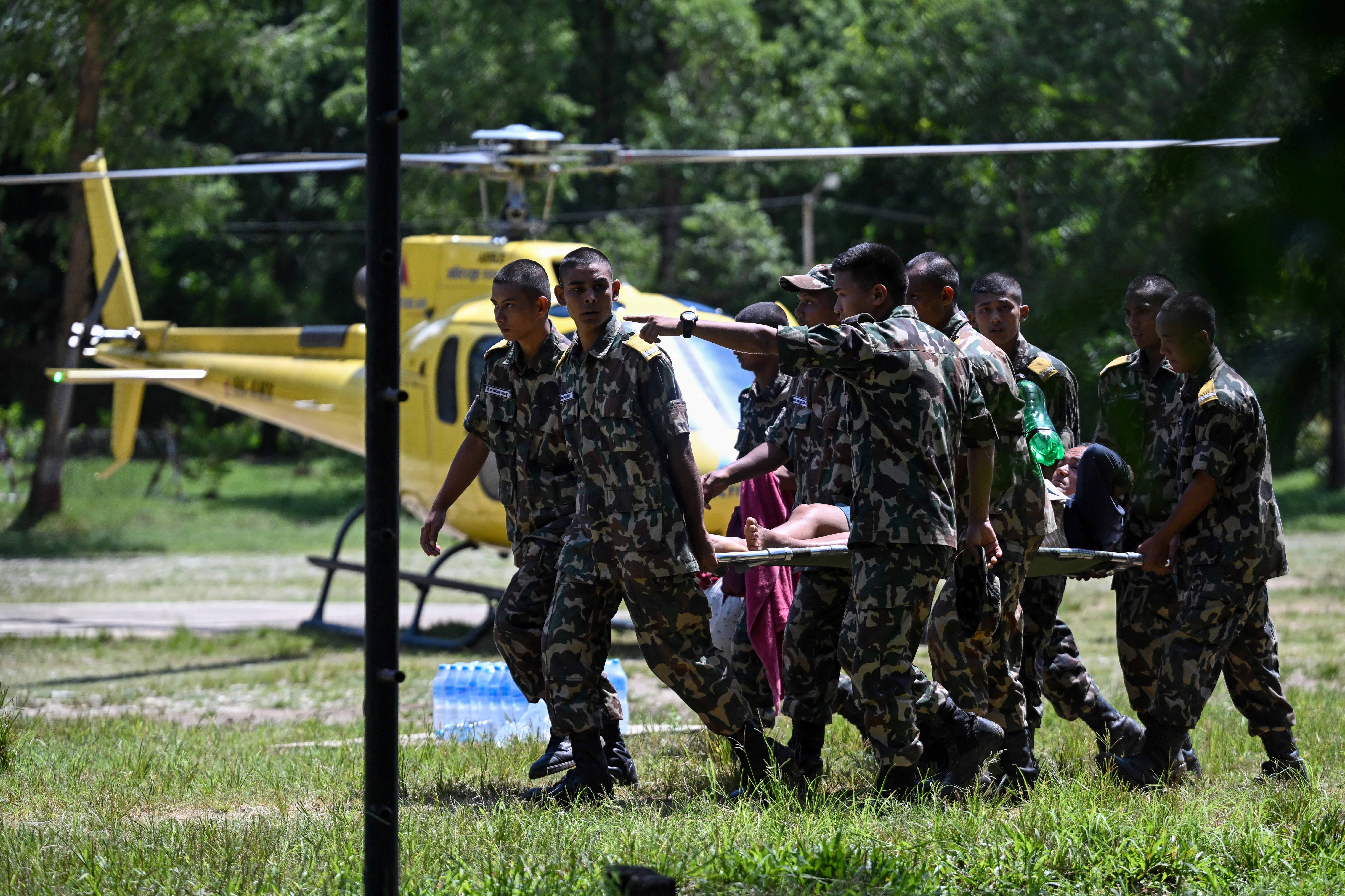 Army personnel rescue flood-affected residents using a helicopter following flash floods, as they arrive at an army camp in Battar Bazar town in Nepal’s Nuwakot district