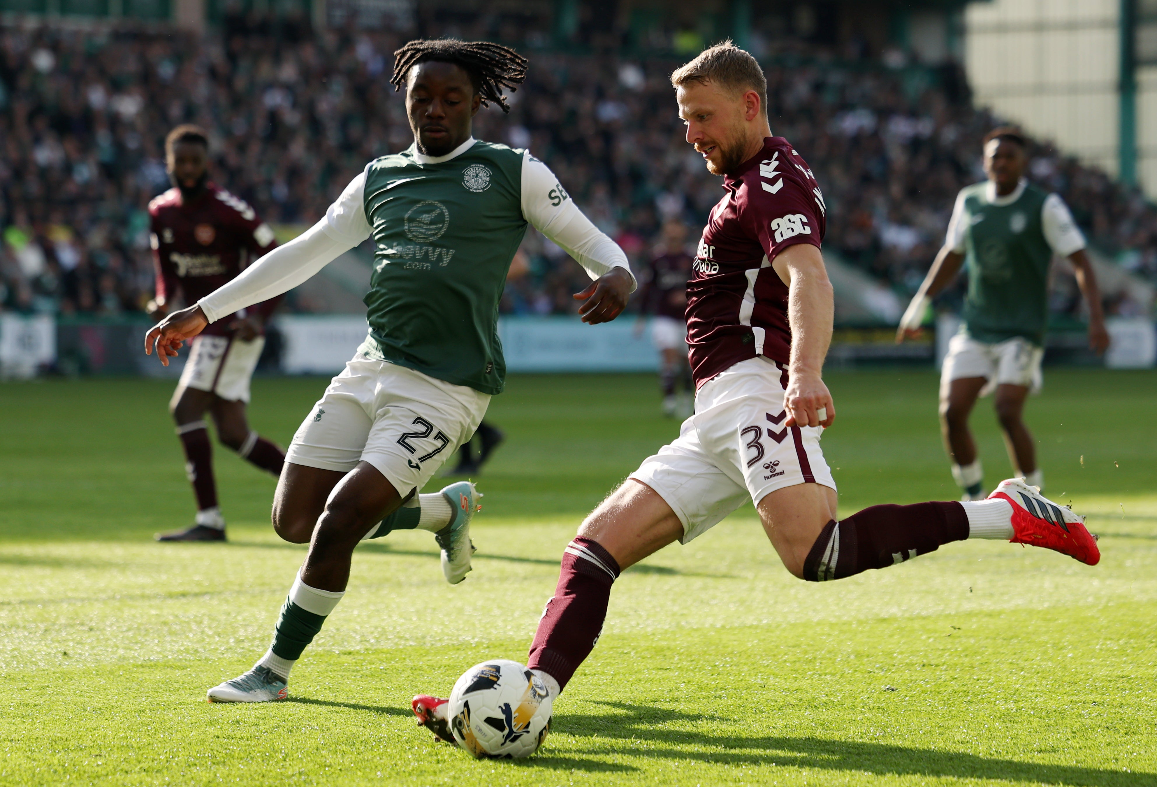 Stephen Kingsley of Heart of Midlothian crosses the ball while under pressure from Kanayo Megwa of Hibernian during the William Hill Premiership match
