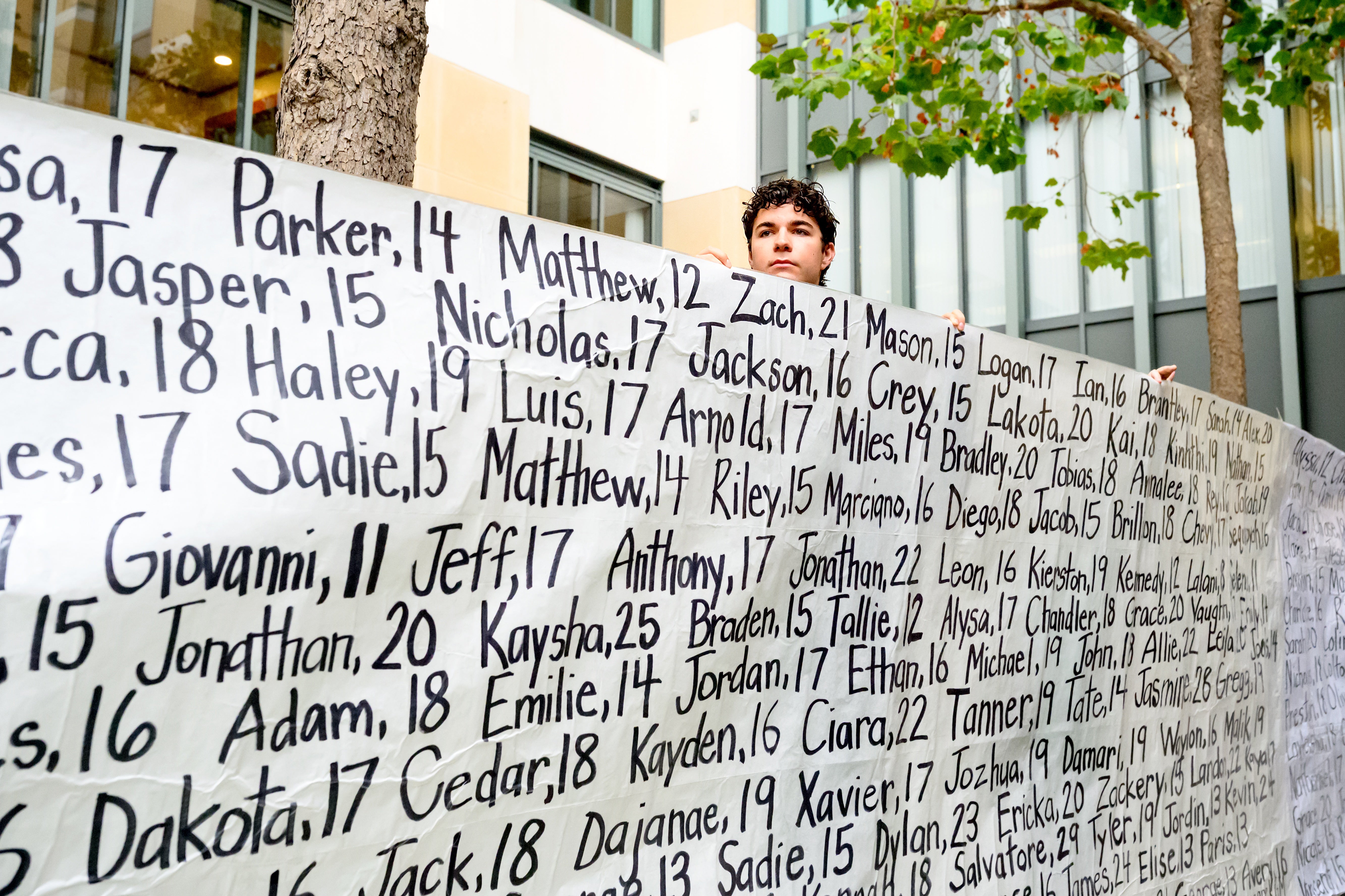 A campaigner holds a banner with names of young people who advocates say died as a result of social media in California, US (Noah Berger/AP)