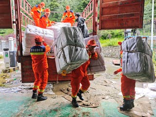 Rescue workers carry relief supplies in Gyirong county, Tibet