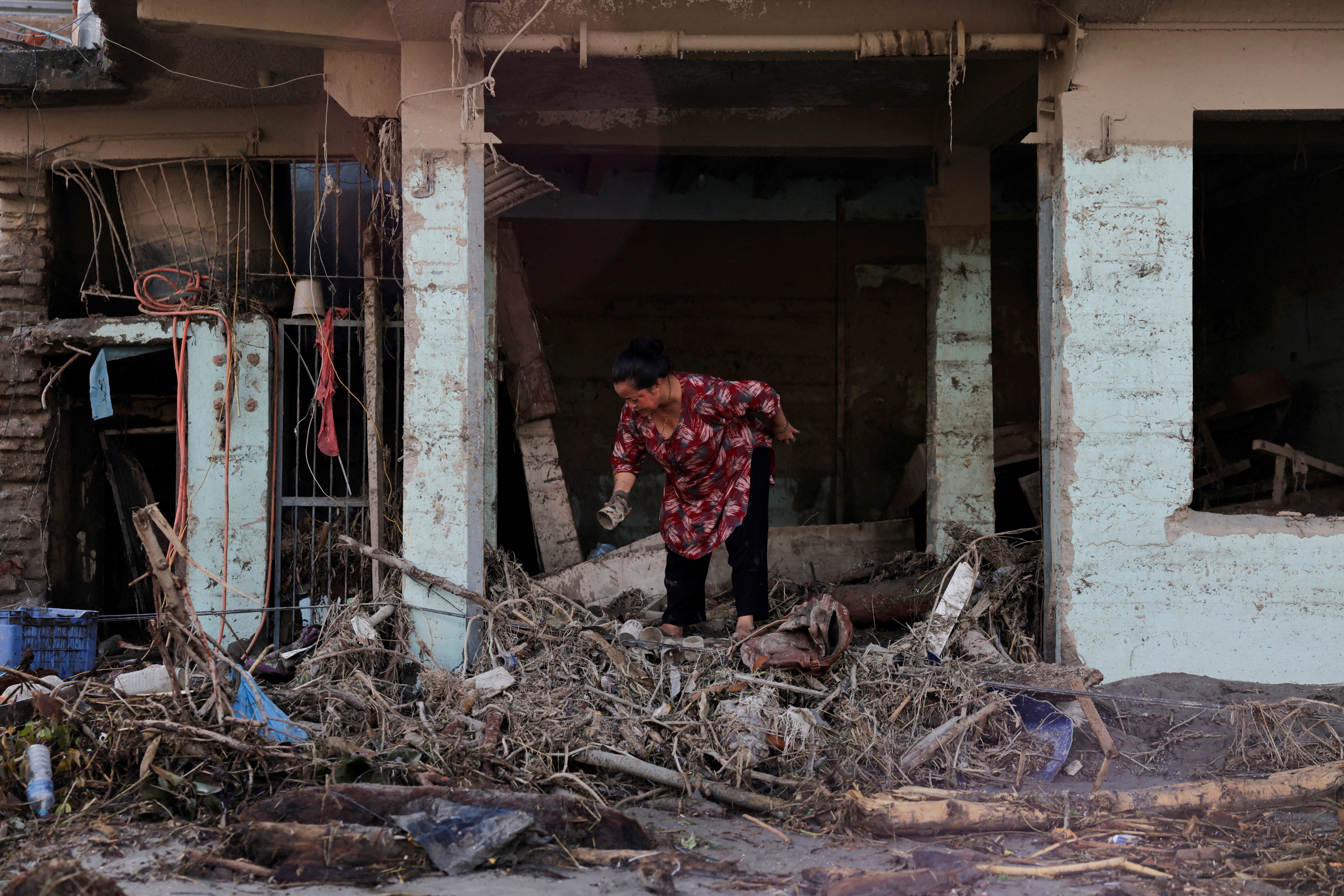 A woman searches for her belongings at a damaged shop following flash floods and a mudslide in Trishuli, Nuwakot district, Nepal, 28 August 2026 (Reuters)