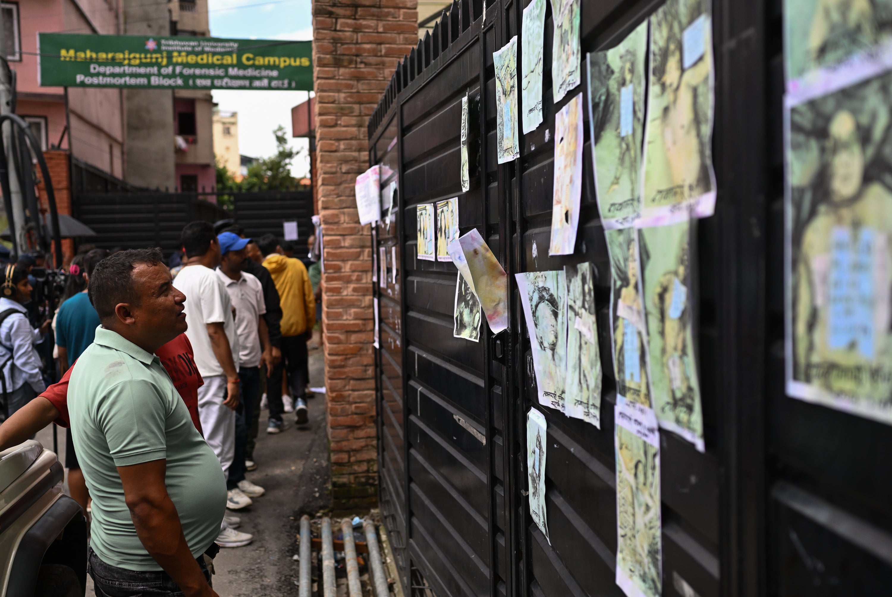 A man looks at images depicting victims of the recent flash floods on the gate of the morgue at the Maharajgunj Medical Campus (Getty)
