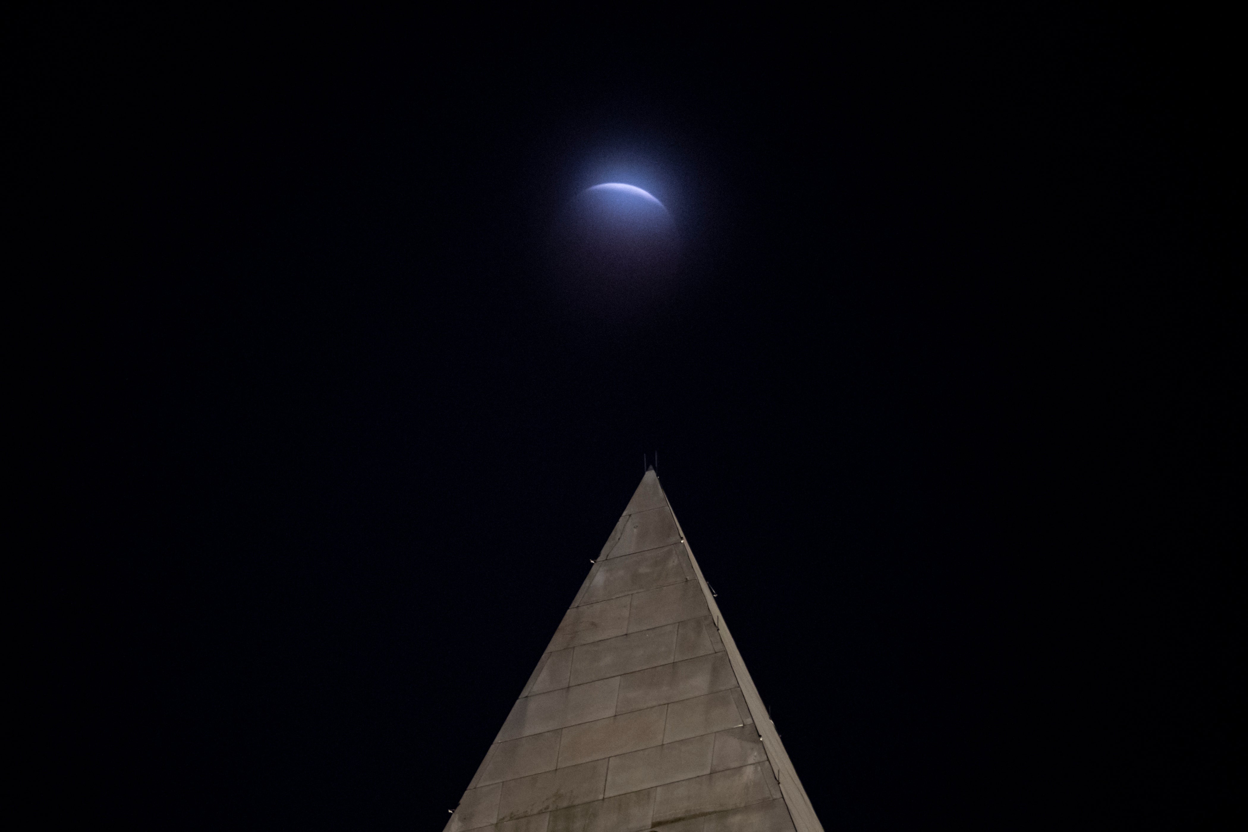 A lunar eclipse of the Moon is seen through clouds behind the Washington Monument. (AP)