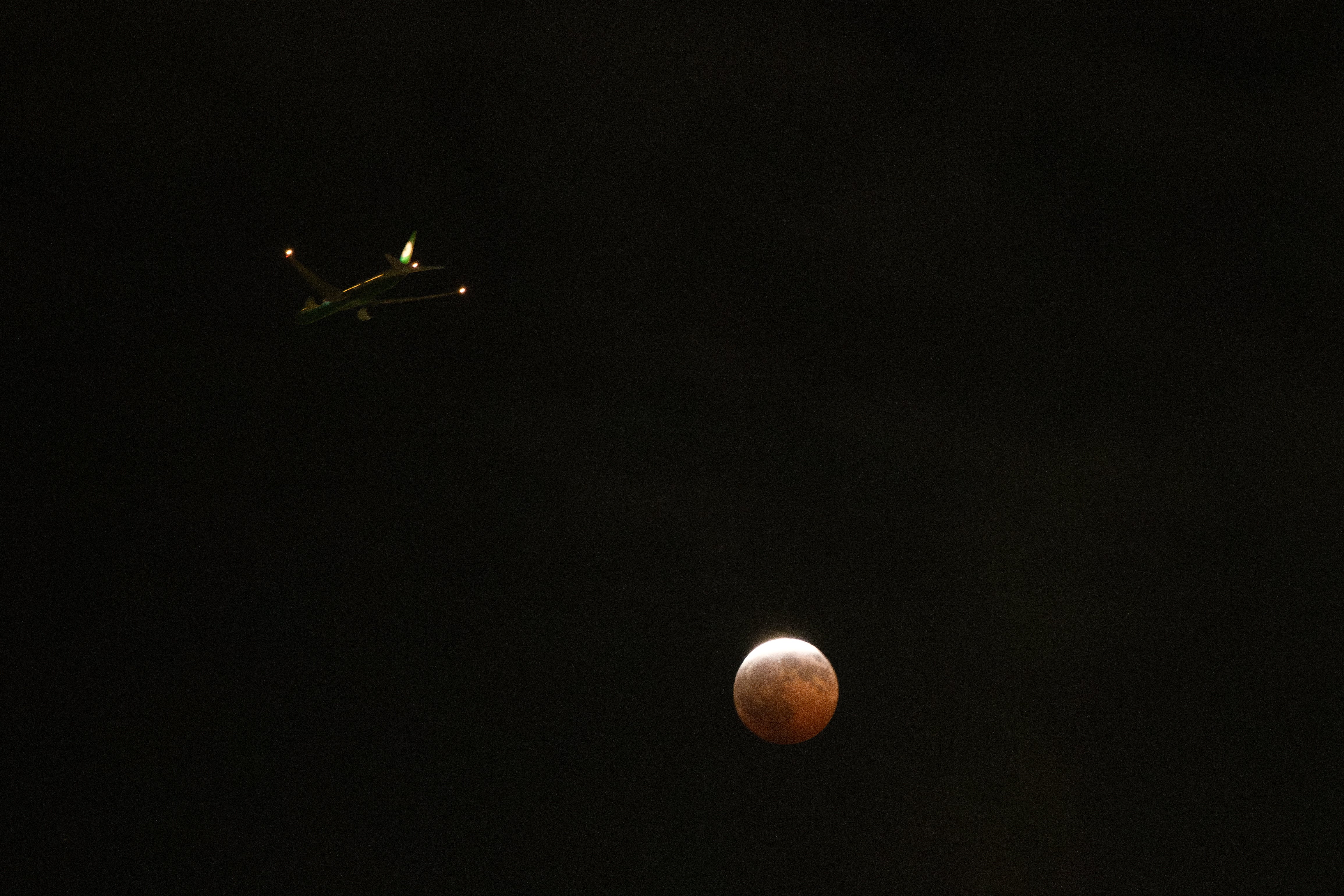 An airplane flies past a partial lunar eclipse in Los Angeles, (AP)