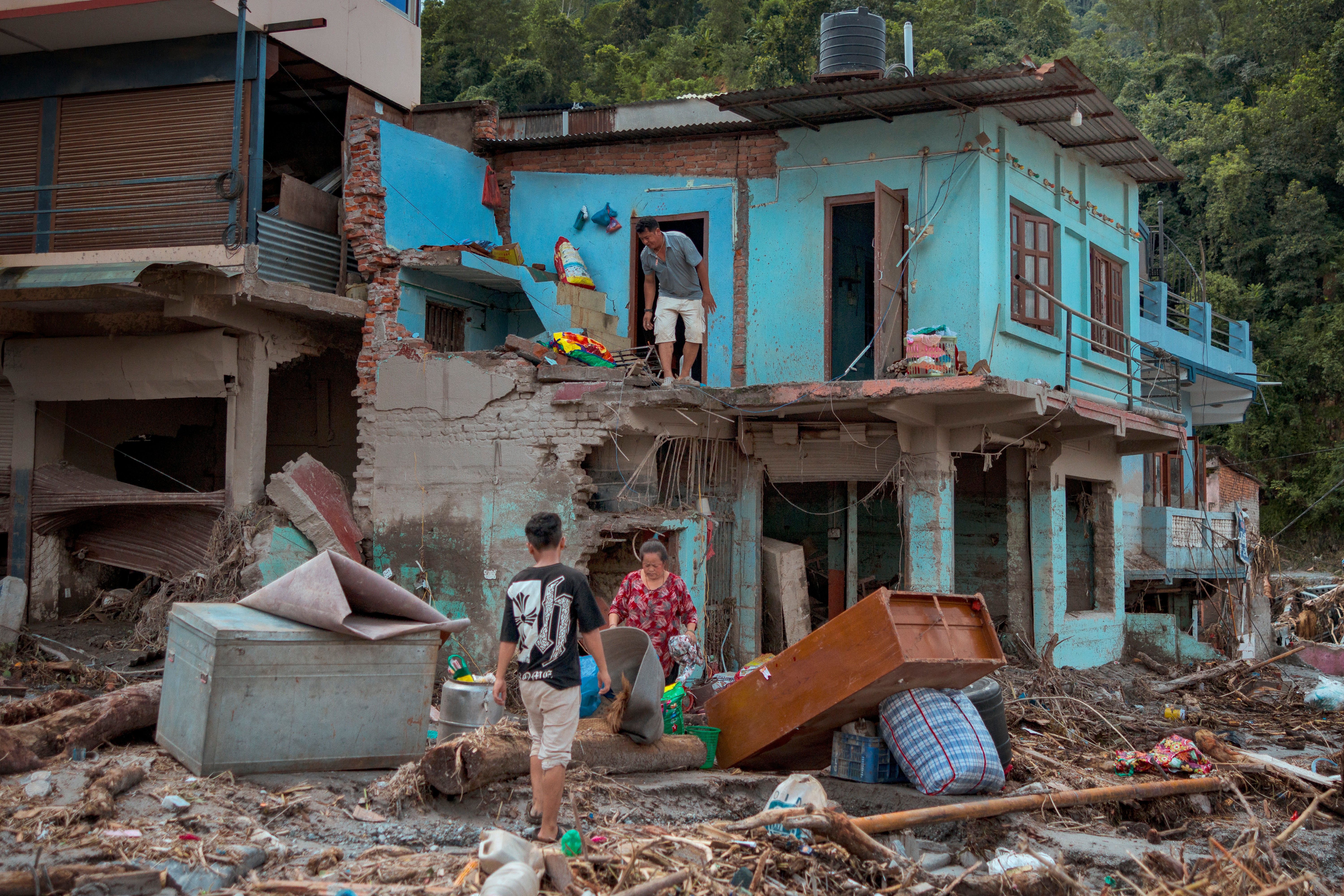 Residents salvage belongings from their destroyed home following flash floods