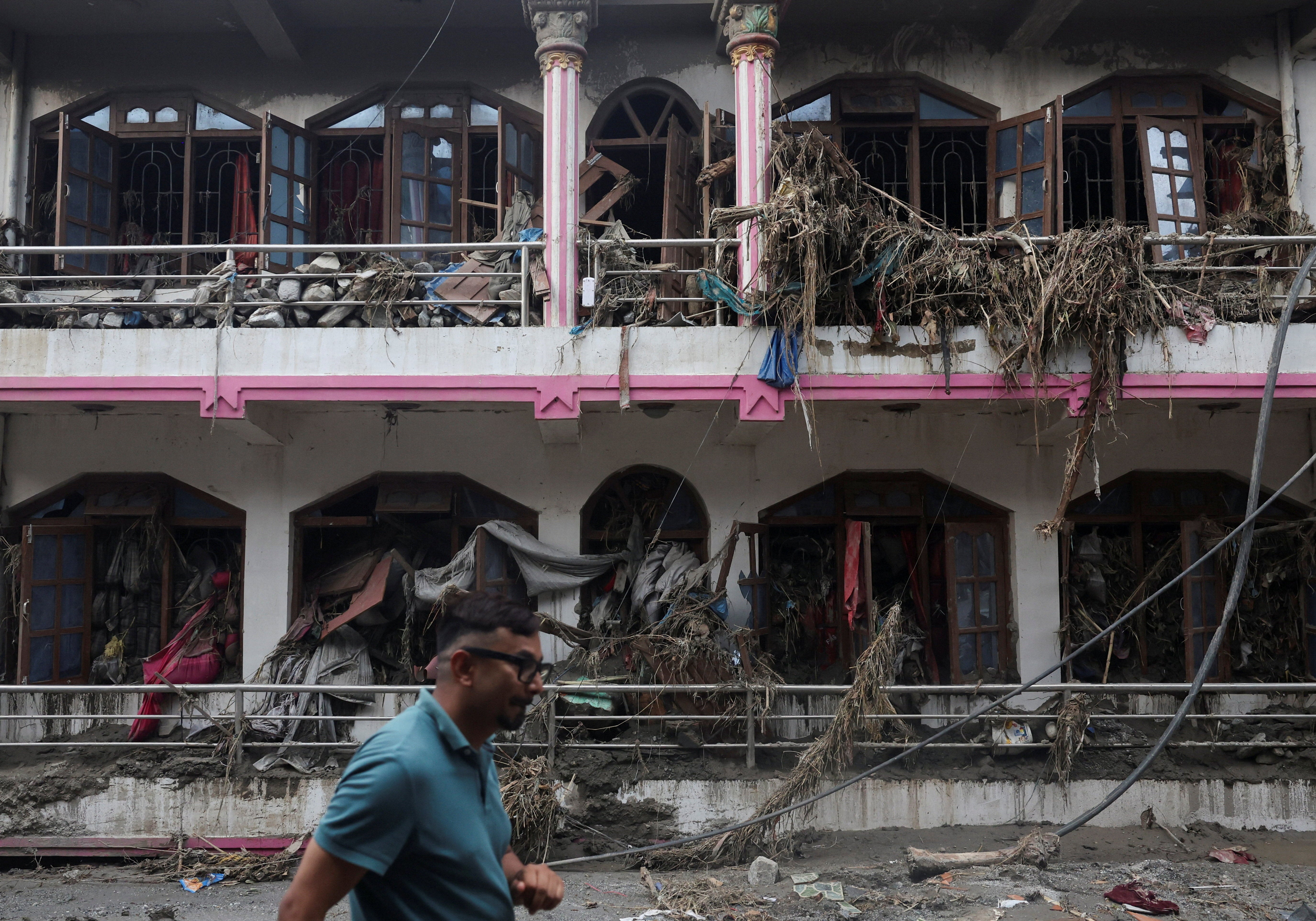 A man walks past a damaged house after flash floods and mudslide, at Devighat, Nuwakot district, Nepal