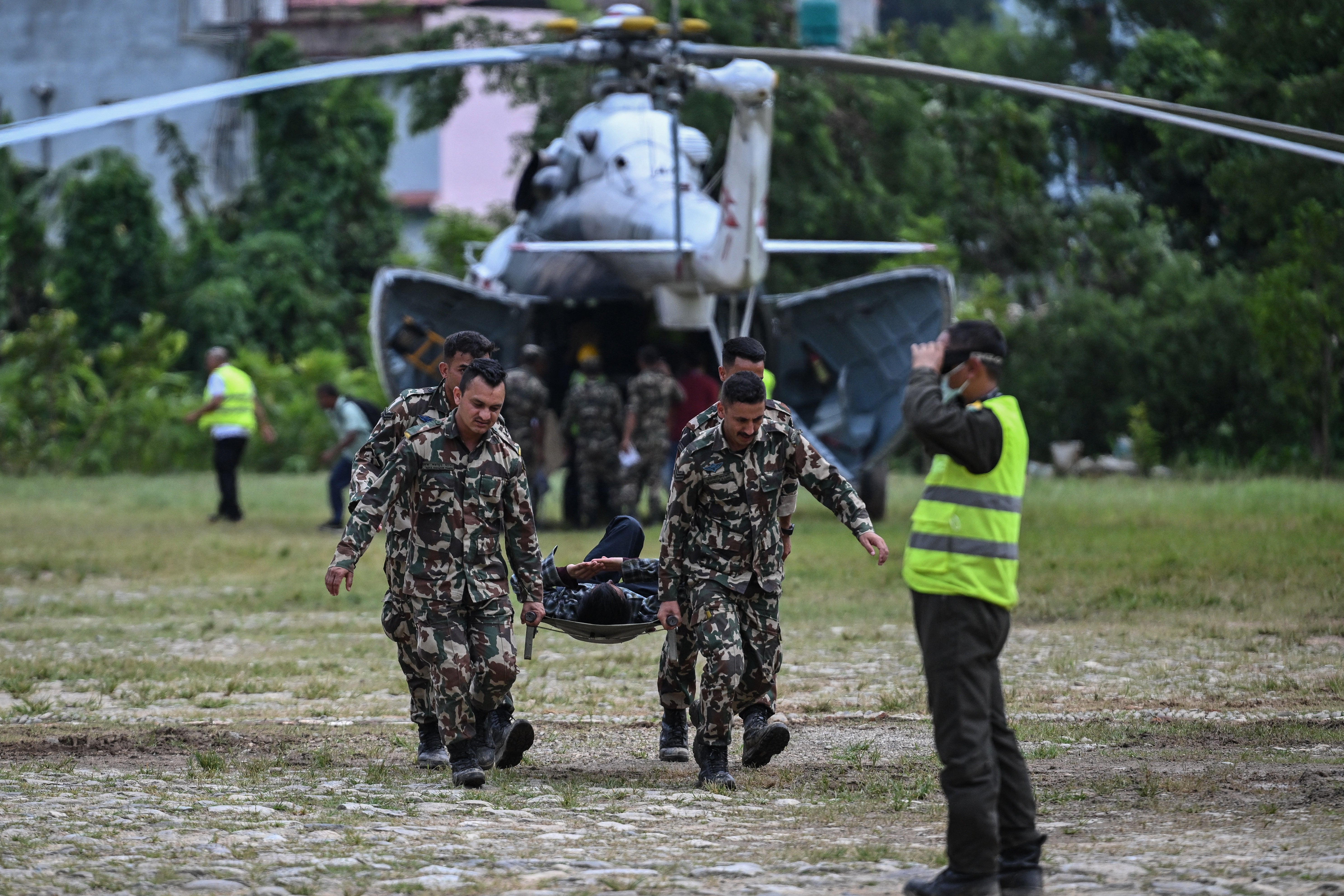 Army personnel carry an injured man during a rescue operation in the aftermath of flash floods, at Trishuli camp in Nuwakot district