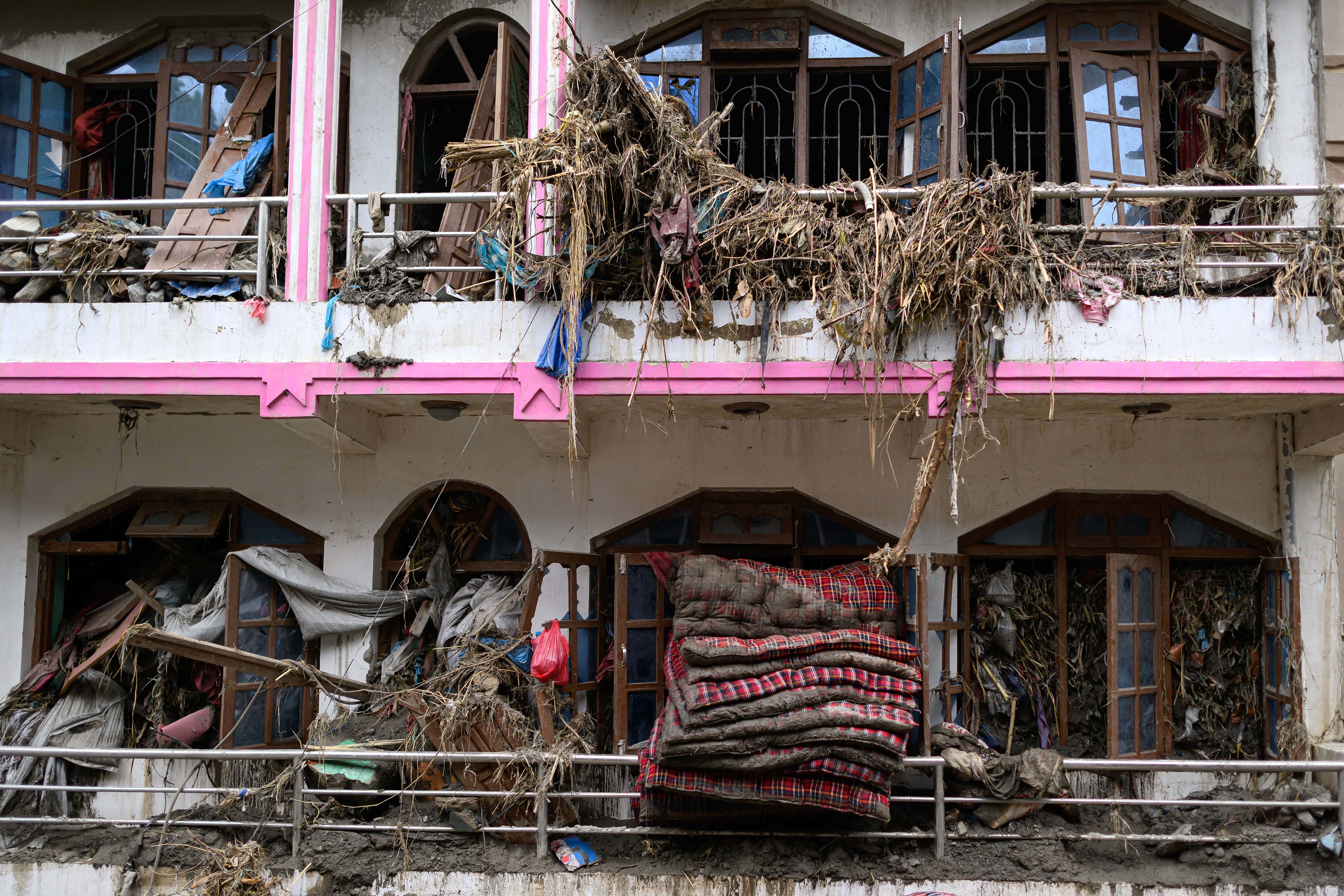 Mattresses and debris is seen coming out of windows of a damaged house in the aftermath of flash floods at Devighat in Nepal's Nuwakot district on August 29, 2026. Nearly 3,000 people were still missing on August 29 and 633 confirmed dead after flash floods and landslides hit the Nepal-Tibet border. (Photo by MANAN VATSYAYANA / AFP via Getty Images) (AFP/Getty)
