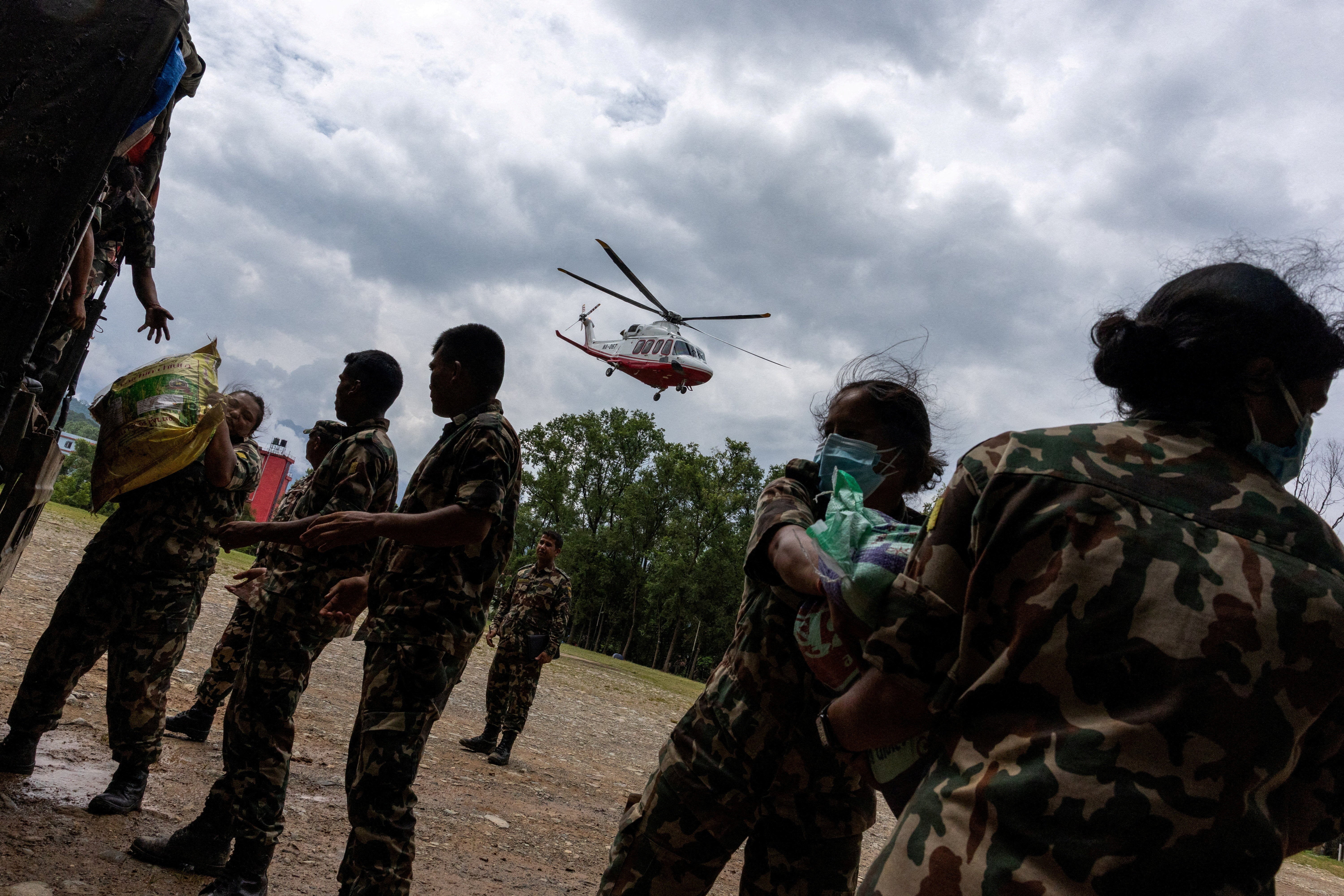 Members of the Nepal Army load relief material as a helicopter containing relief supplies takes off to areas affected by deadly flash floods and a mudslide, as it drizzles at the Maithili Barrack, an army training centre, in Trishuli, Nuwakot district, Nepal